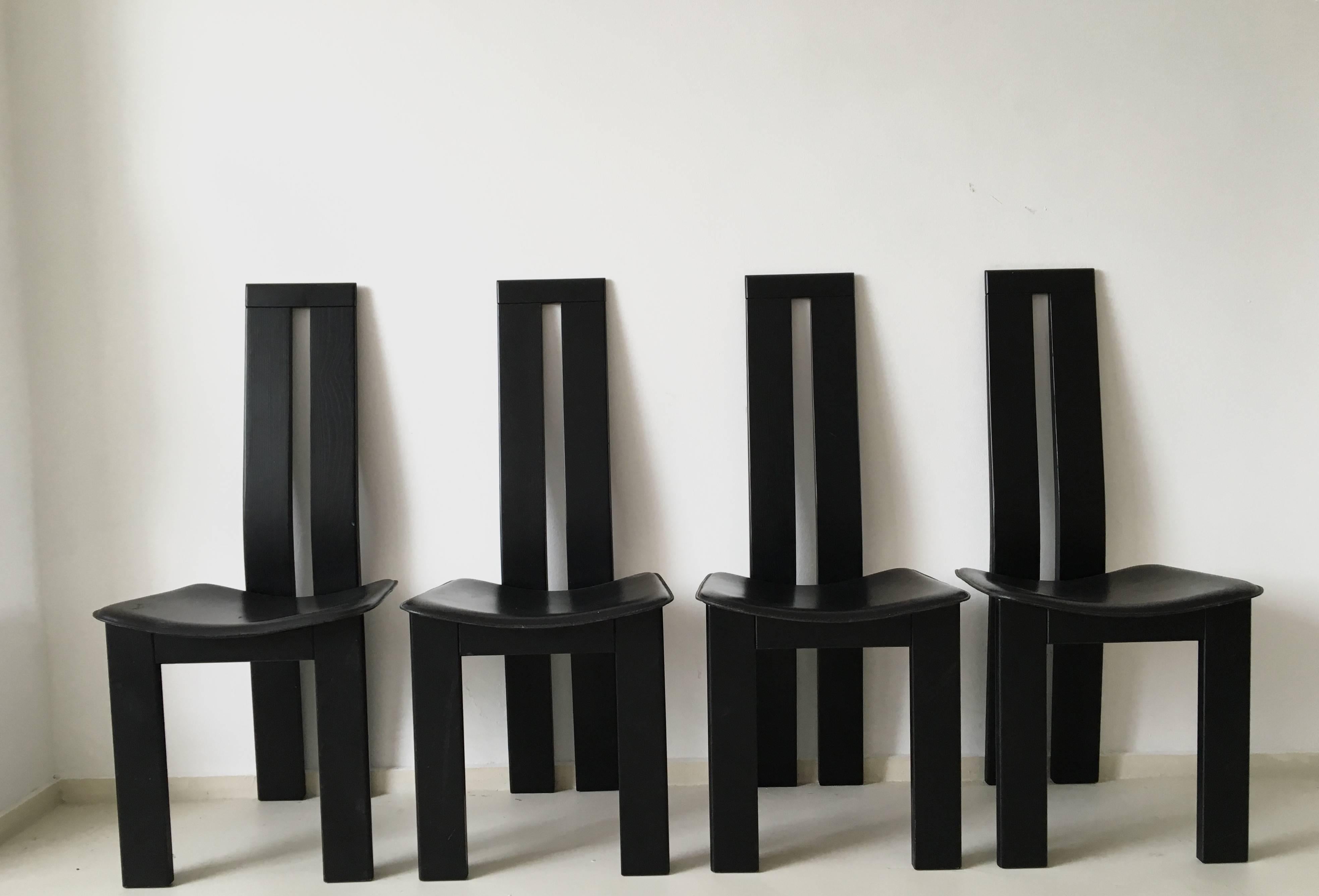 Set of four dining chairs designed by Pietro Constantini for Ello, Italy, circa 1970. The chairs are made from black lacquered wood with stitched black saddle leather seats. The chairs are labeled underneath the seat, and remain in a good condition