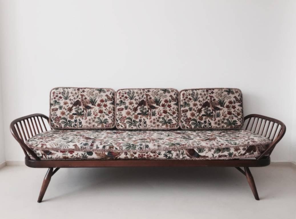 This daybed was designed in the 1950s by Lucian Ercolani and produced by Ercol in United Kingdom. It features a Classic wooden frame with original colorful fabric. The webbing has been renewed. This couch is labeled and remains in a good condition