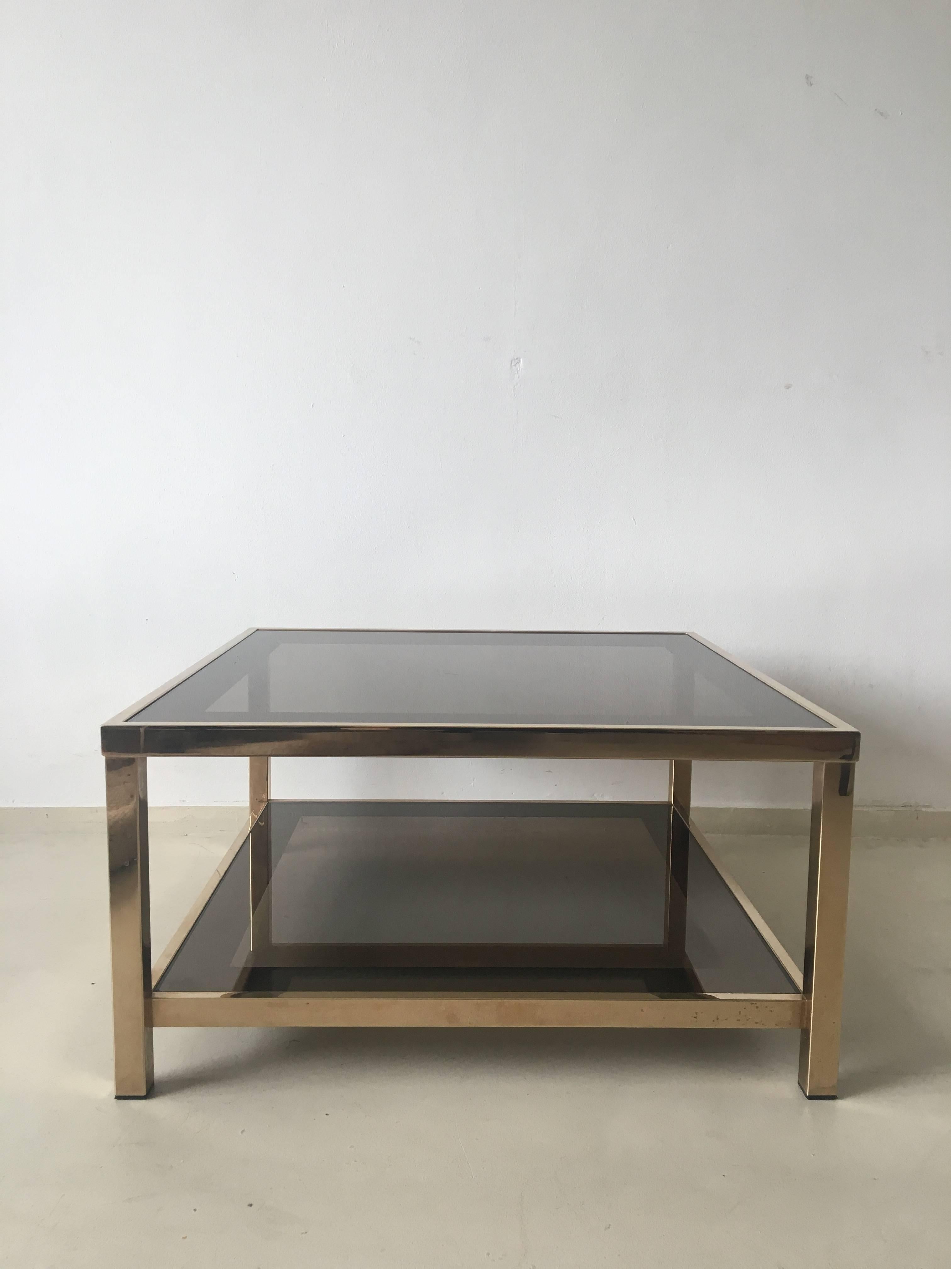This exclusive two-tiered table was designed with a gold-plated metal frame and wonderful mirrored borders in the glass. It remains in a good vintage condition with wear consistent with age and use. The table is marked with a certificate.