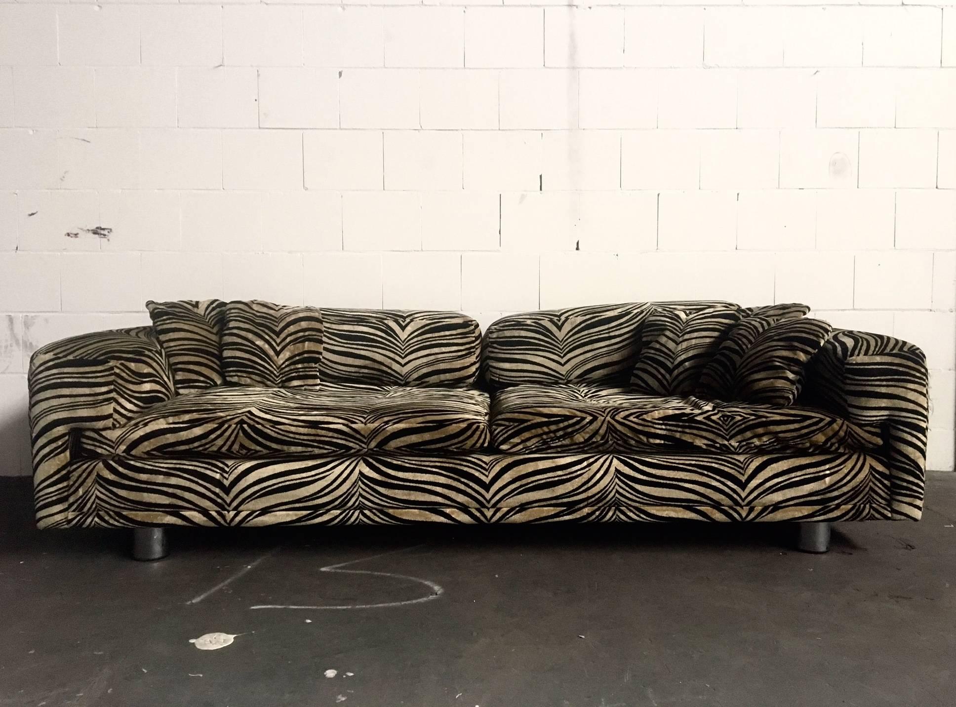 This stunning rectangular sofa comes with a soft and shiny animal print. It has huge soft cushions, perfect for lounging in. Also a set of five small cushions is included. The feet are in metal with wood. Fits very well in a Hollywood Regency style