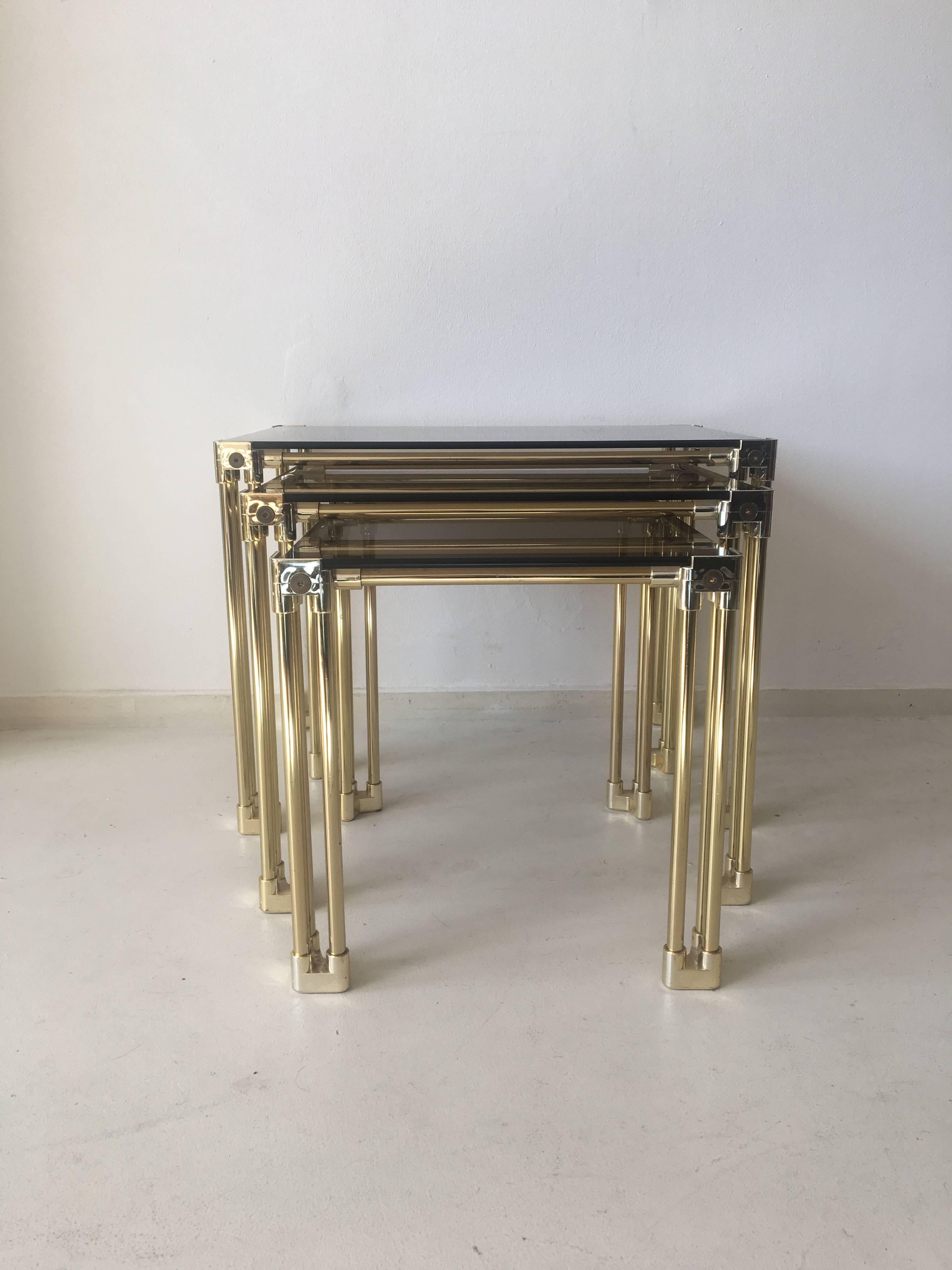 This set of three Hollywood Regency style stacking tables, come with a brass frame and corners in artificial material. Table tops are made of smoked glass. The three of them remain in a very good vintage condition with normal wear.

NOW ON SALE