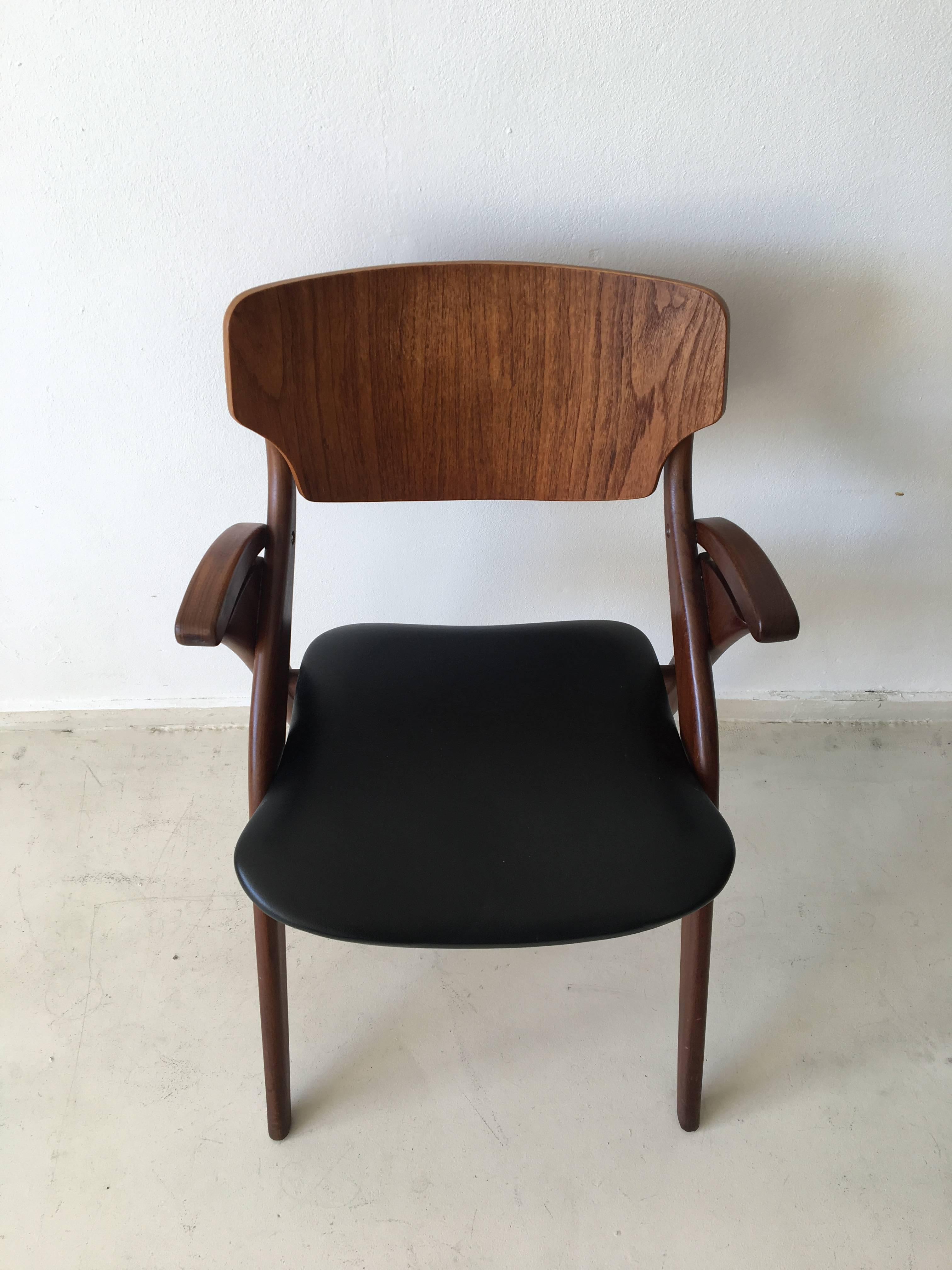 This beautiful Danish design comes with a sculptural frame in teak. At both sides, there are pieces of faux leather, the same as it's upholstery. This chair is in excellent condition with only minor signs of age and use.