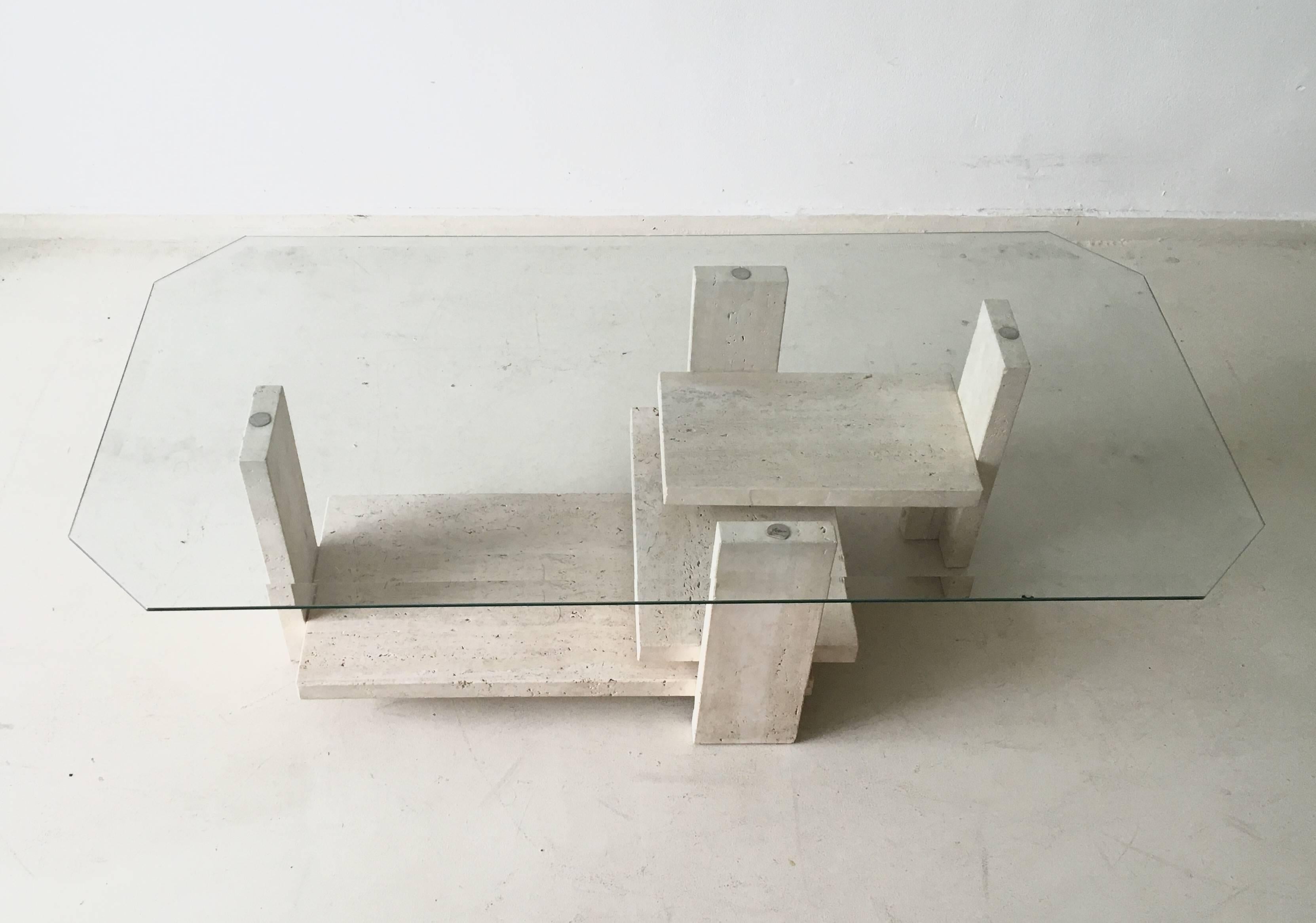 This wonderfull Brutalist coffee table was designed by Willy Ballez in Belgium, circa 1970s. It consists of a well designed travertine base with a beveled glass top. The table is in very good condition with a small chip and light scratches to the