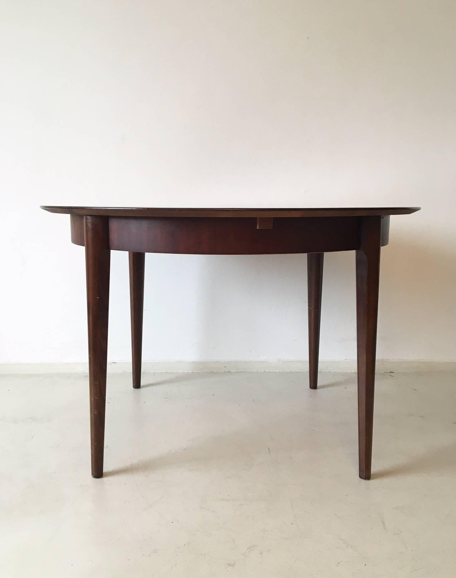 This wonderful extendable dining table was designed and manufactured by Lubke in Germany during the 1960s. It features a frame in wood with a Mahogany colored veneer. It's feet are made of solid wood and are slightly tapered, also they are