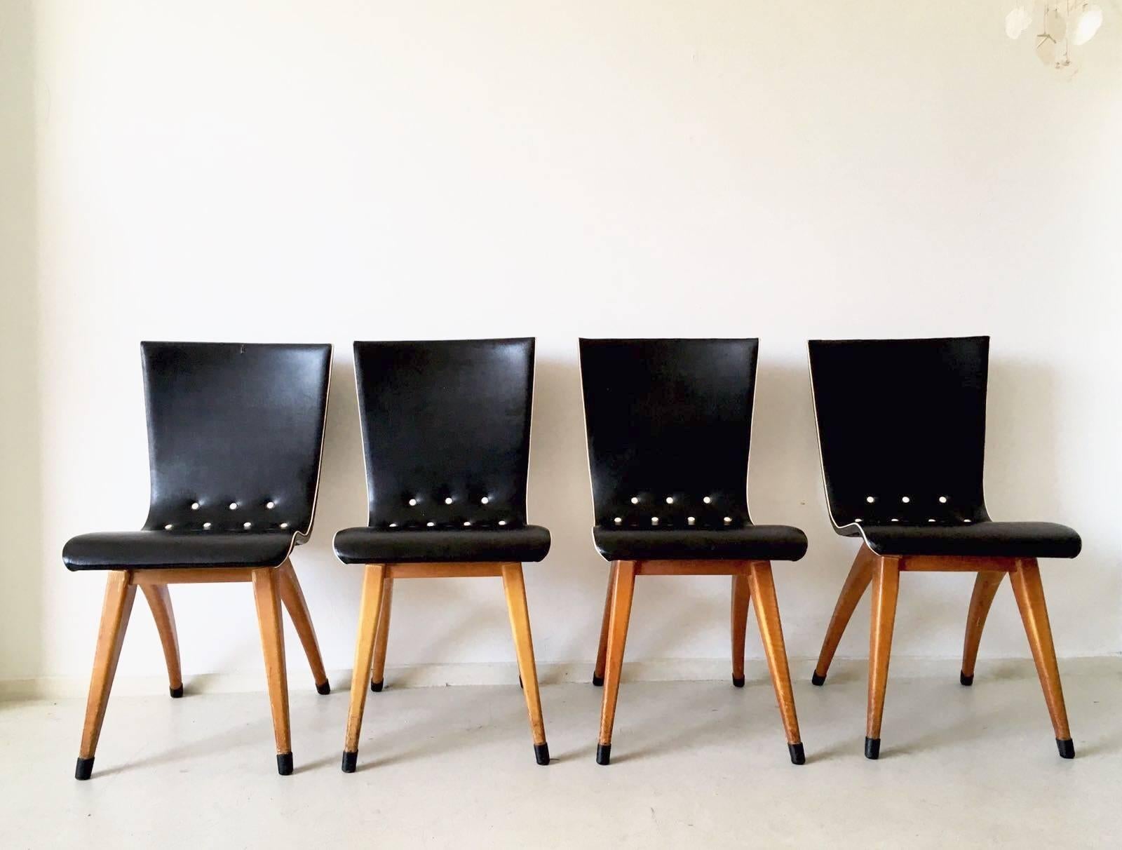 This set of four black beautiful chairs were designed and manufactured in the Netherlands, circa 1950s. They feature frames in wood (asumed to be fruitwood) and original black and white leatherette upholstery. Wonderfully finished with original