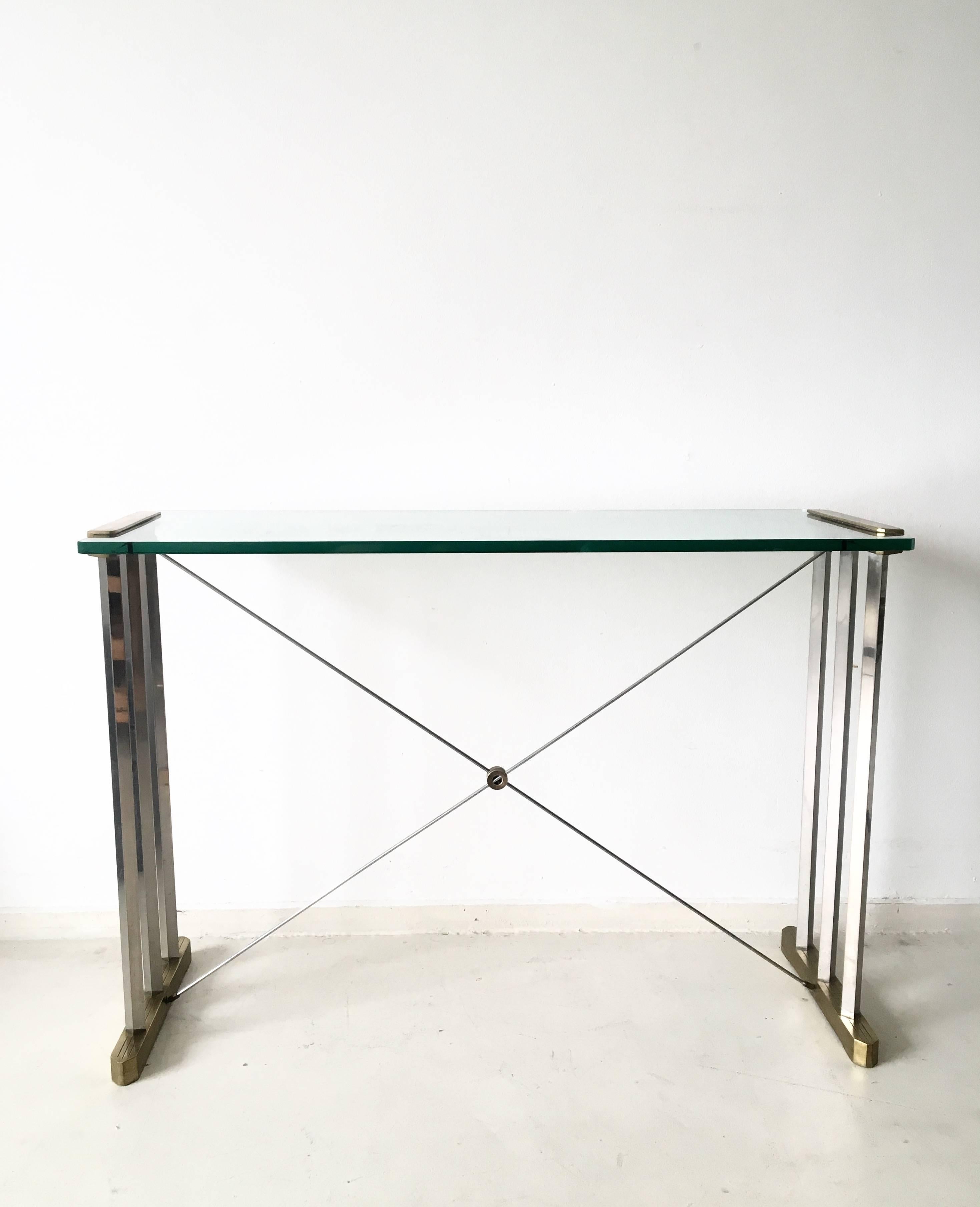 This model, features a metal frame with brass and steel elements and a thick glass top. 
This piece is in a very good condition but has unfortunately one chip on it's glass top. However the glass top can be replaced with another original one for