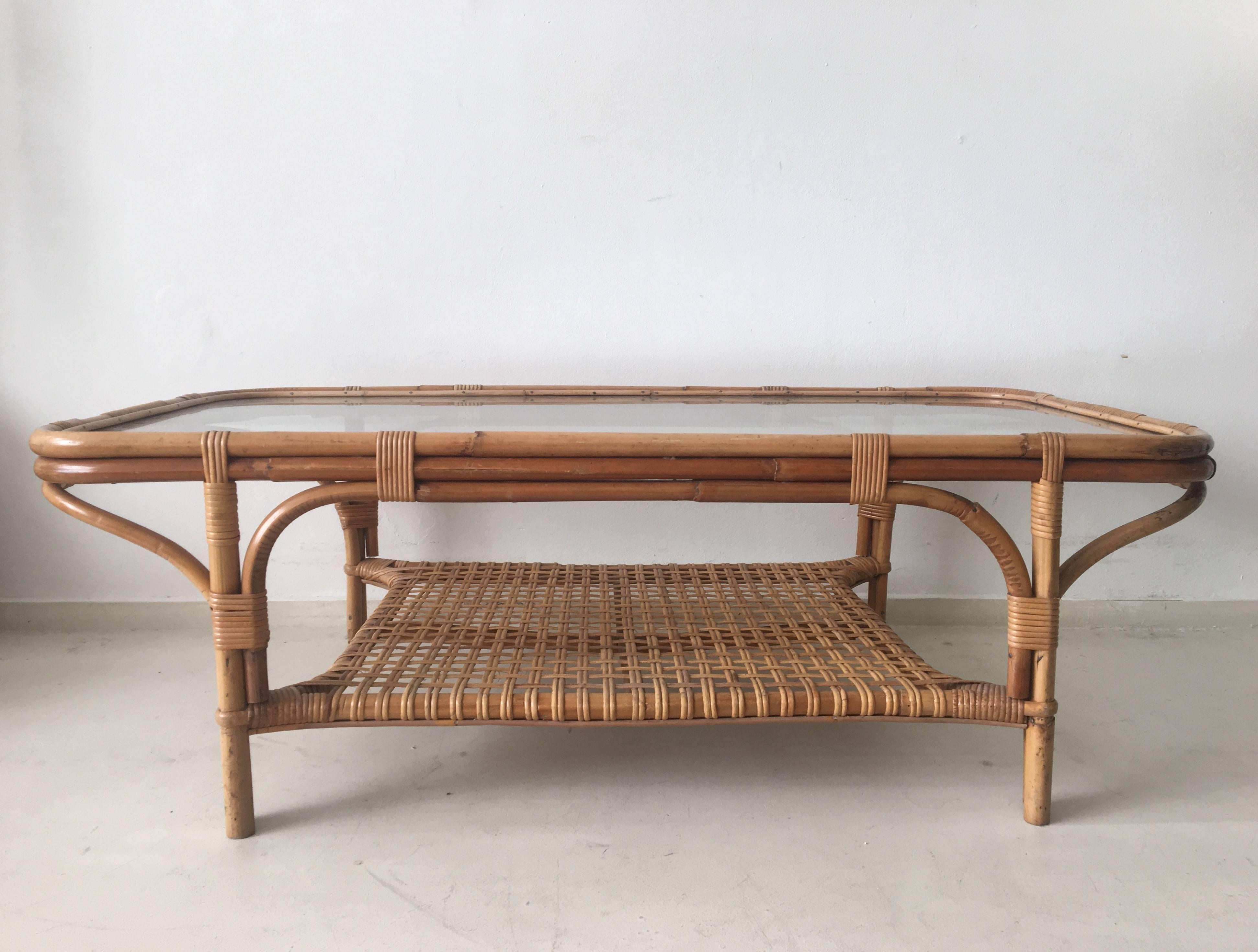 This superb Bohemian coffee table features a woven rattan base and magazine rack, with a bright glass top. It was designed and manufactured in Europe, circa the 1960s. The table remains in super condition with only minor signs of age and use. Some
