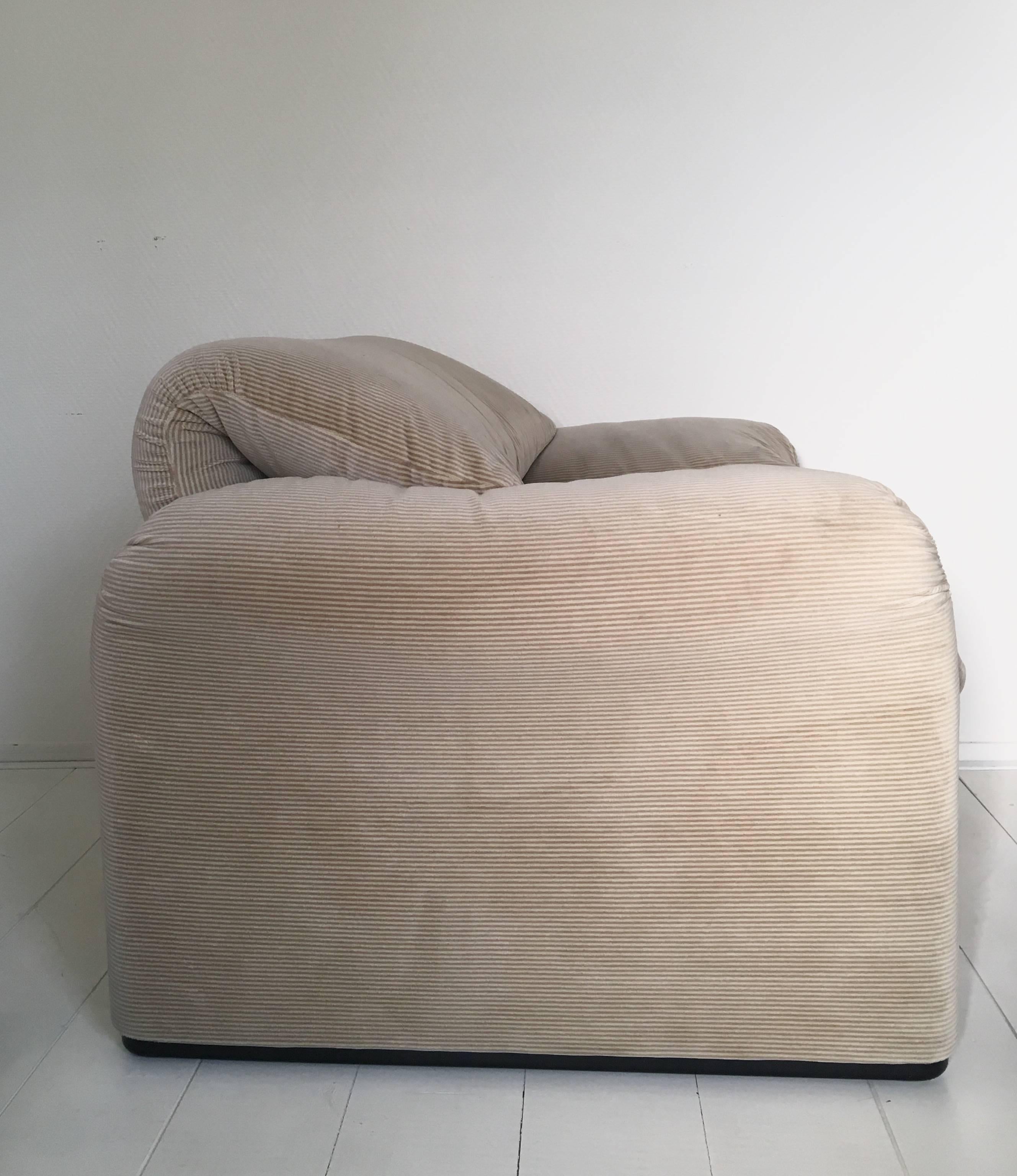 This warm and comfortable armchair, was designed by Vico Magistretti for Cassina in the 1970s. It features a bi-color fabric with subtle stripe pattern in beige and sand. How you will see the exact coloration of the chair, depends on how the light