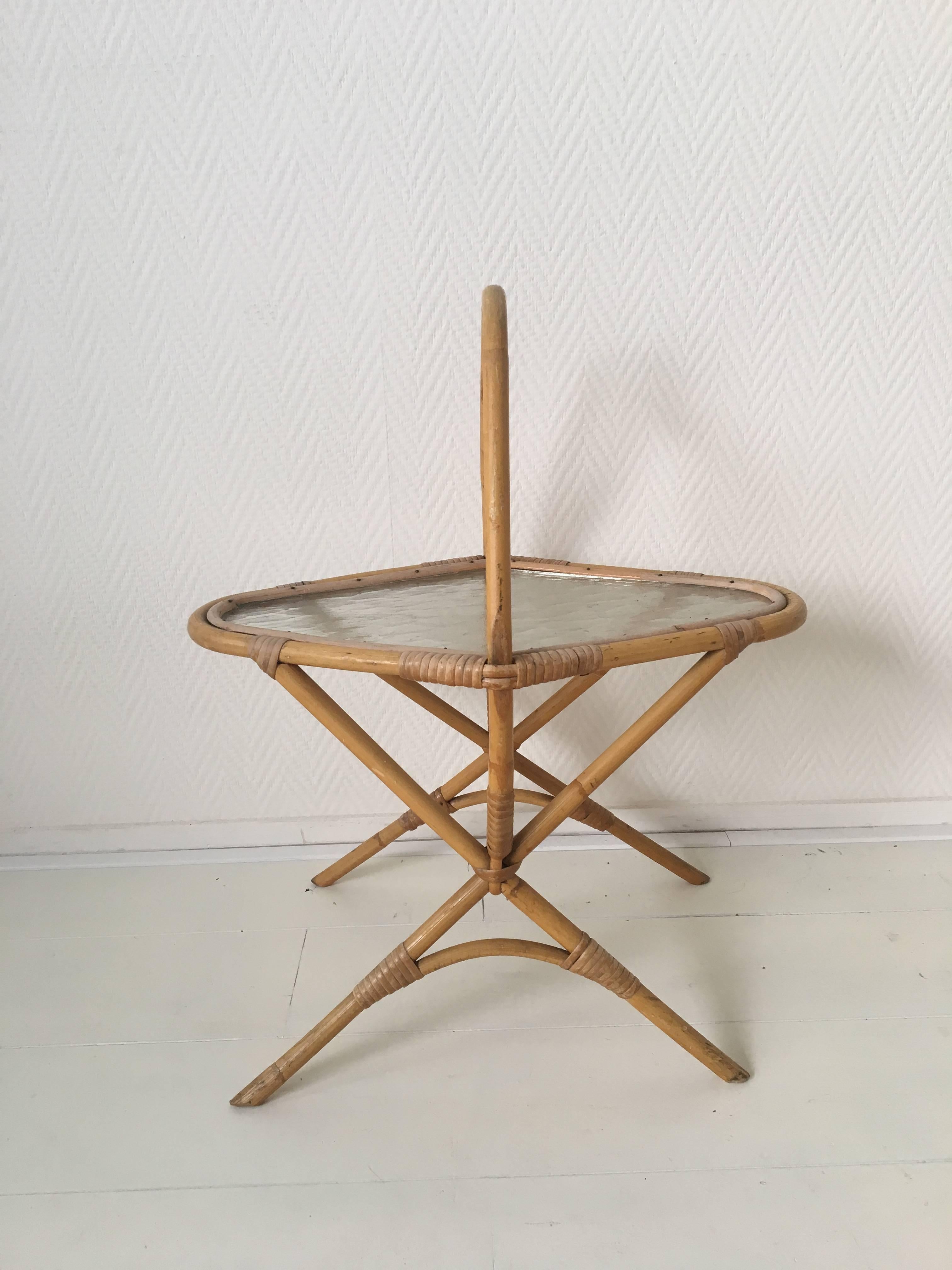 This adorable small side table or planter was designed and manufactured in the Netherlands, circa 1960s. (Very much in style of Rohé Noordwolde). It features a rattan base with a very nice glass top. The table remains in excellent condition and is a