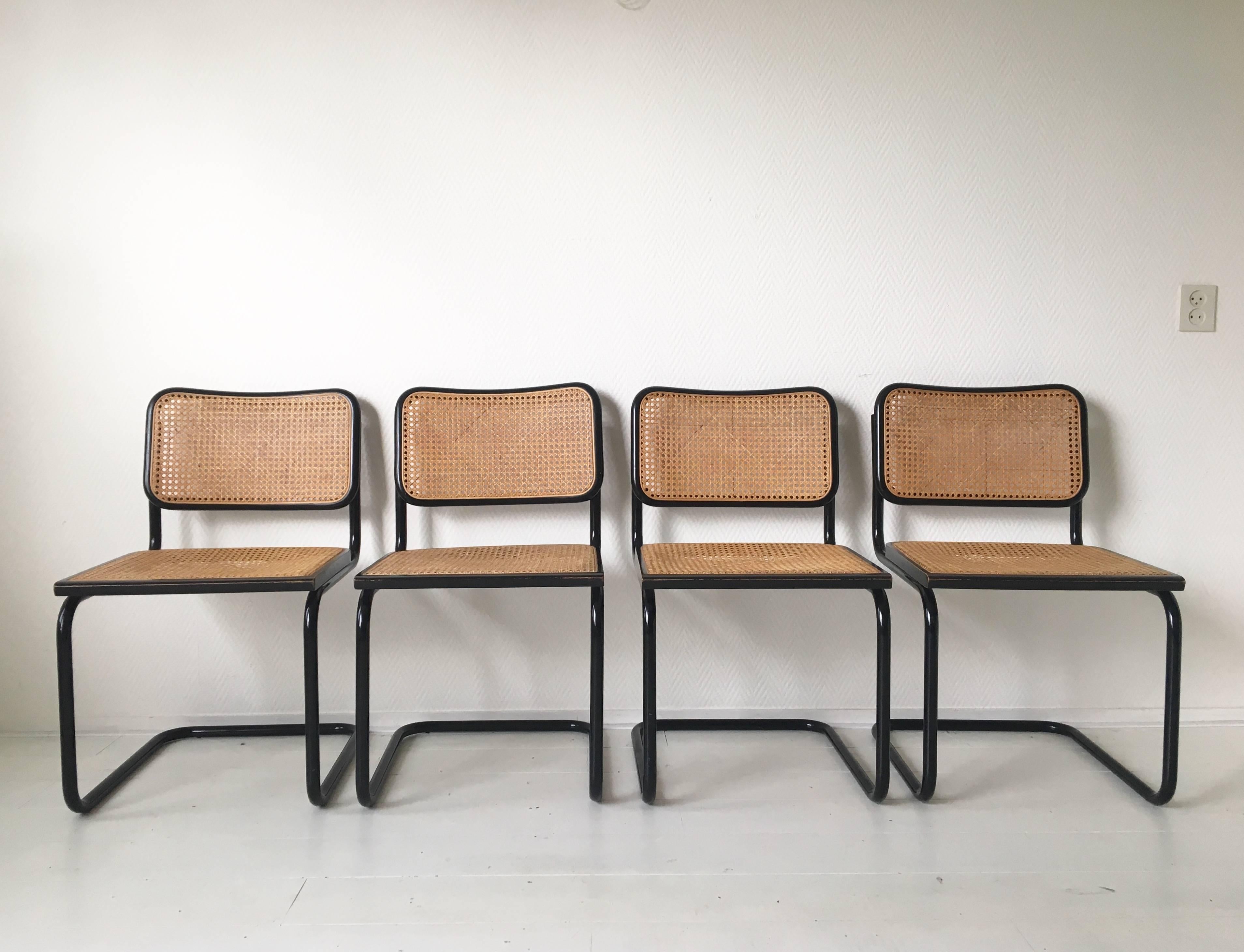 These four iconic chairs were designed and manufactured in Italy, circa 1970s. They feature a black tubular base with caned seats and backrests. The chairs remain in a very good and sturdy vintage condition and show only minimal signs of age and