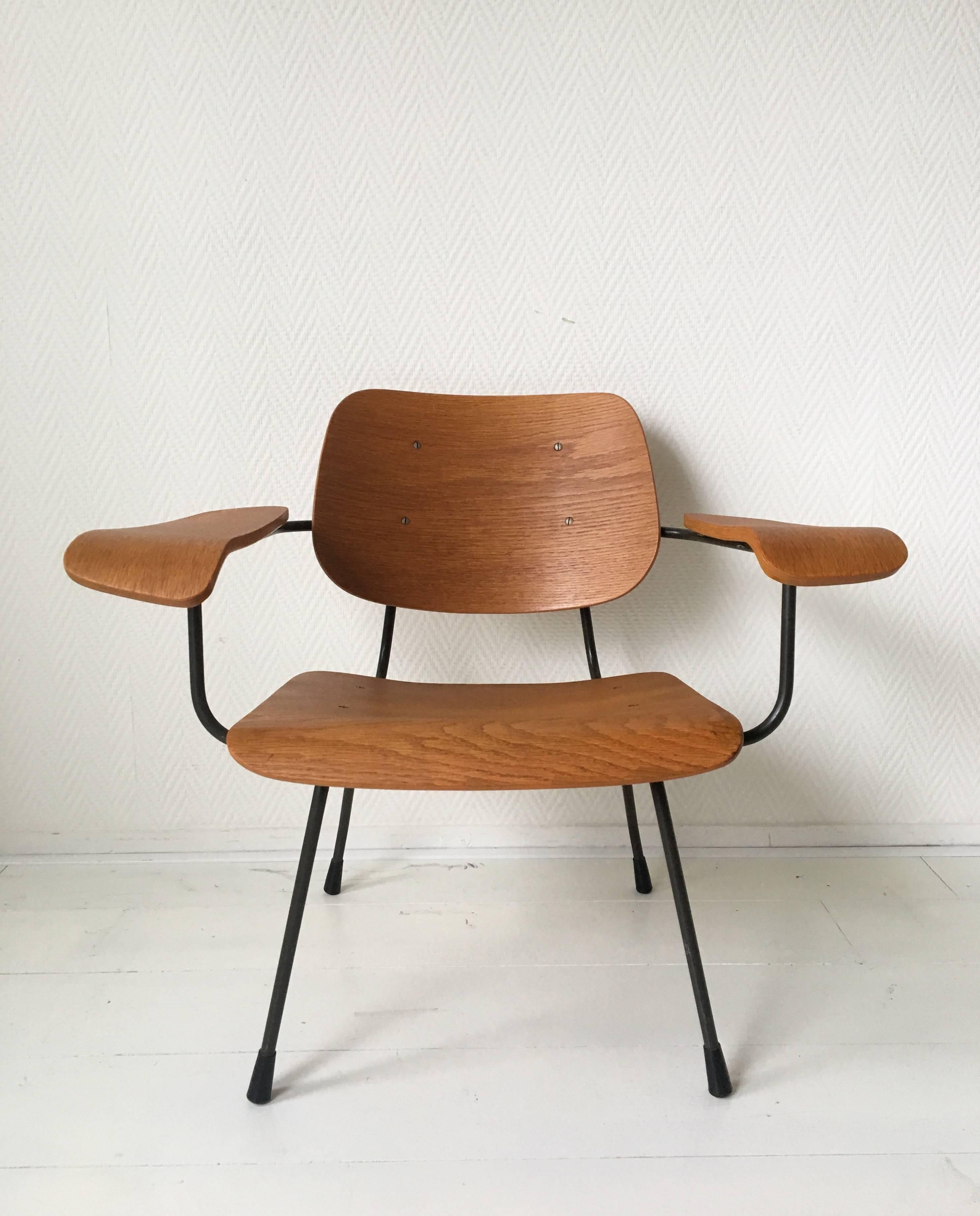 Industrial midcentury design by Tjerk Reijenga for Pilastro in 1962.
The chair features a dark anthracite colored metal frame with armrests, back and seat made from teak plywood. Very good and solid condition, with some small restorations (see: