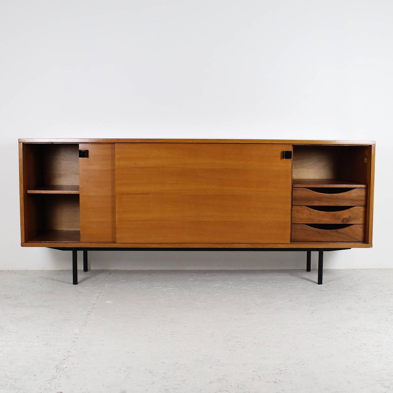 A sleek design for this sideboard by Alain Richard, manufactured by Meubles TV in 1954. The two sliding doors are opening on a set of drawers and shelves providing a good storage capacity. The frame is in elm burr veneer and the tubular legs are