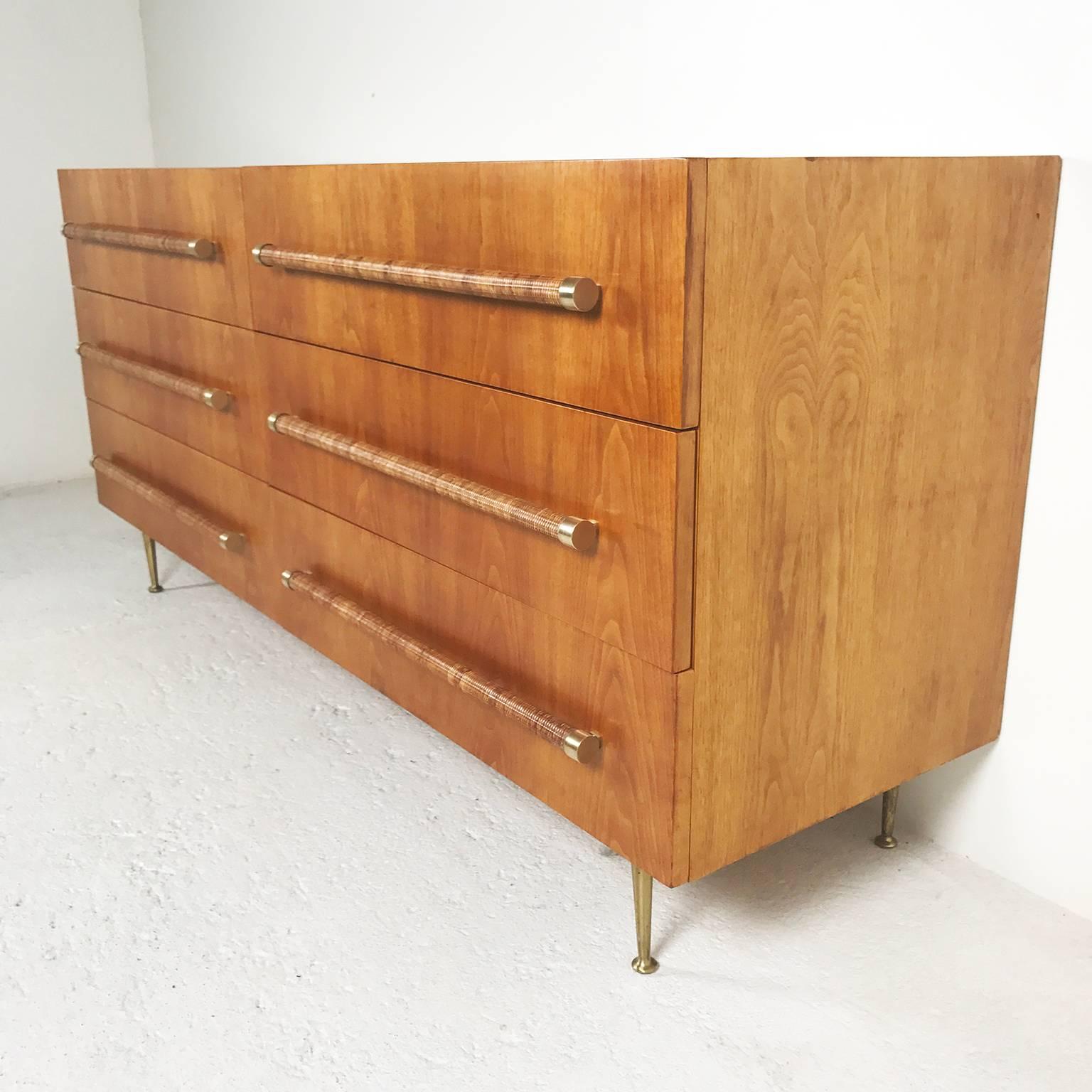 A splendid chest of drawers in walnut by the British designer T.H. Robsjohn-Gibbings for the U.S. manufacturer Widdicomb with six drawers. The handles are in rattan-wrapped and the legs in golden brass. Note: Two spare handles are available.
