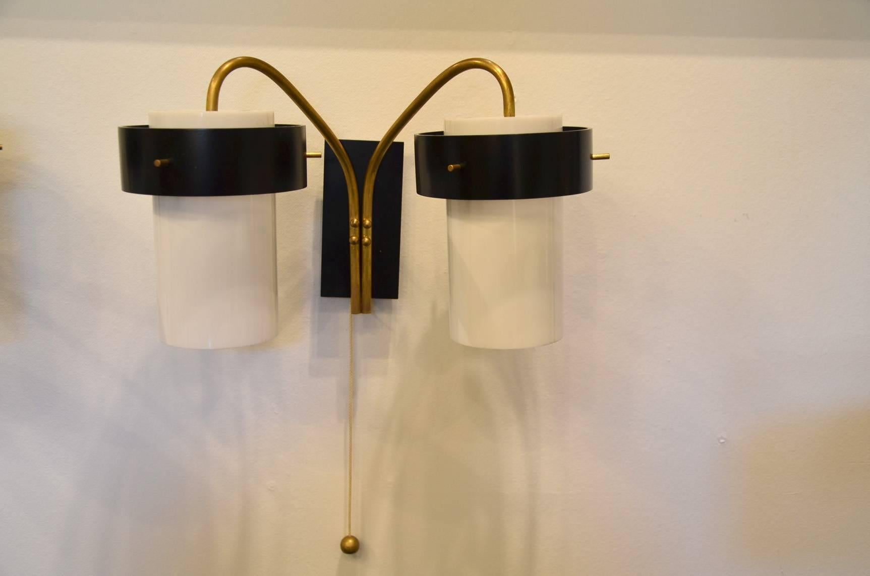 Brass structure and black and white pvc. 
Double light for each sconce.