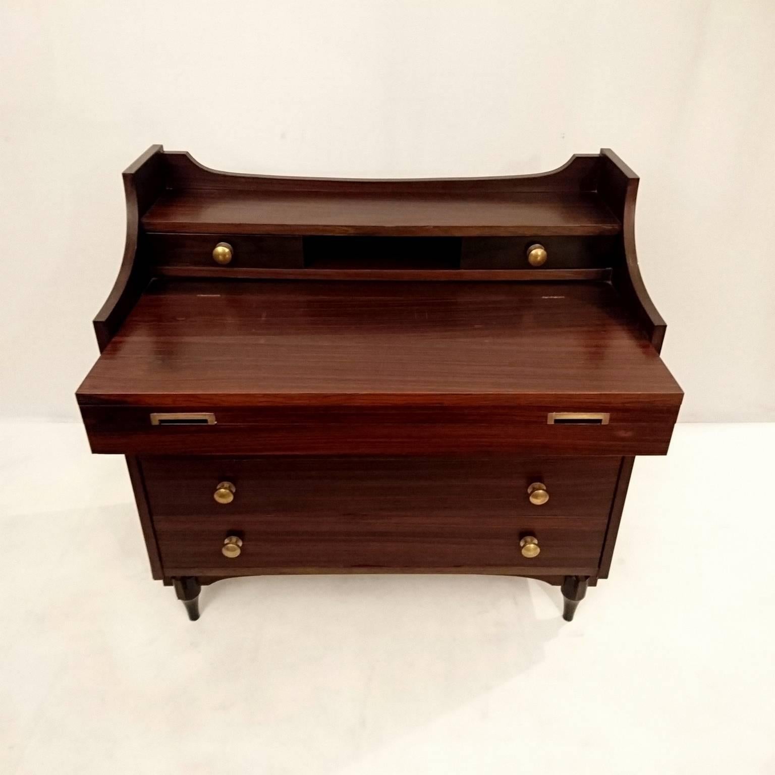 This model SC284 chest of drawers or dressing table was designed by Claudio Salocchi and produced by Sormani, Italy in 1963. It is made from rosewood with brass details. The top drawer contains a fold-out mirror so it can be utilized as a dressing