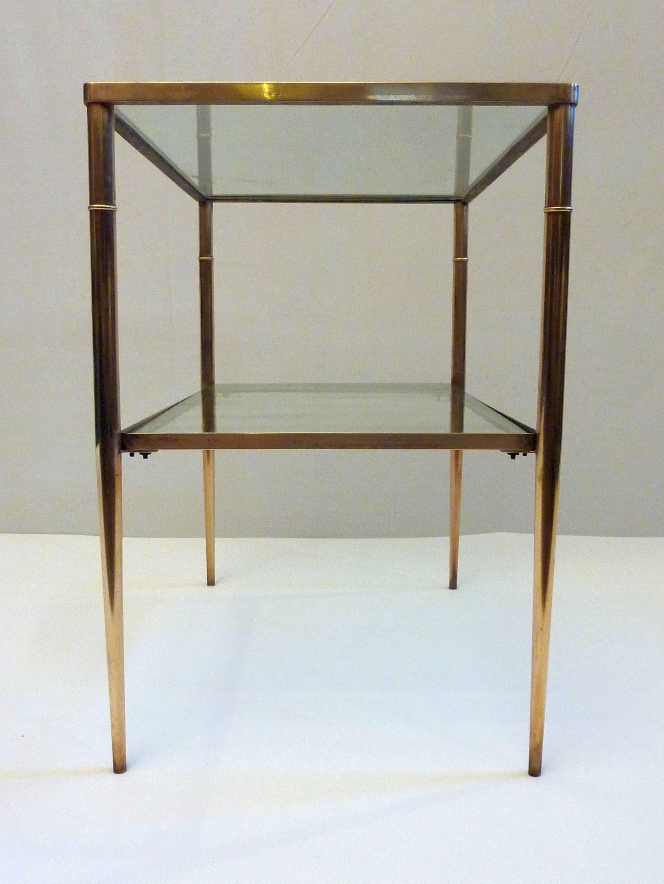 Elegant side table with two levels. It has a brass frame with clear glass shelves.