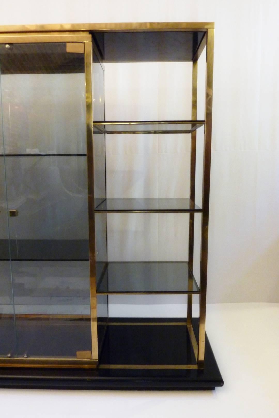 Vitrine and shelving unit produced in Italy. Stands on a solid wood base painted in black. The glass is slightly smoke colored.