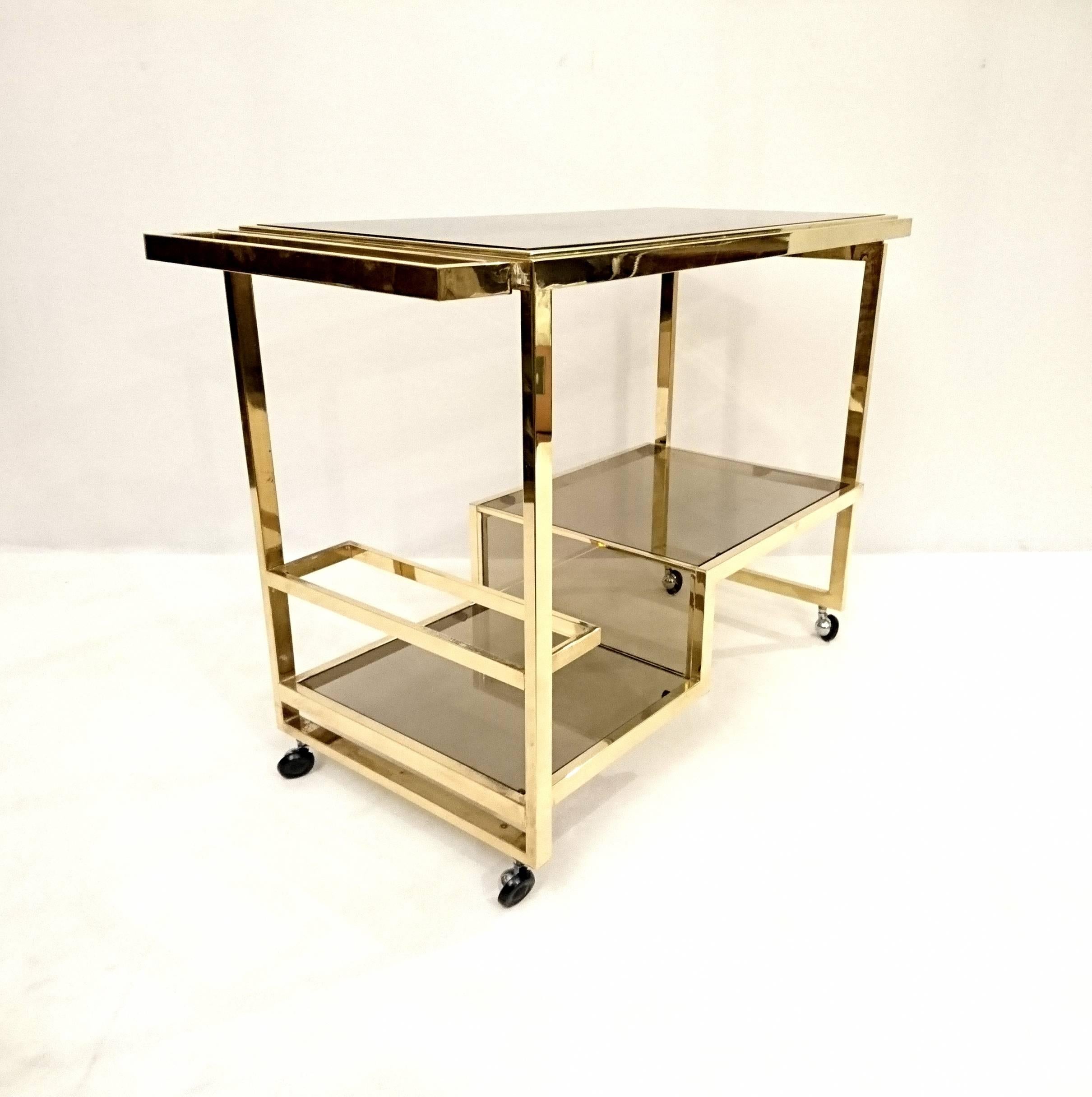 Elegant and solid bar trolley in full brass and smoked glass. Marked Nazaret on the glass. Original wheels in excellent working order.