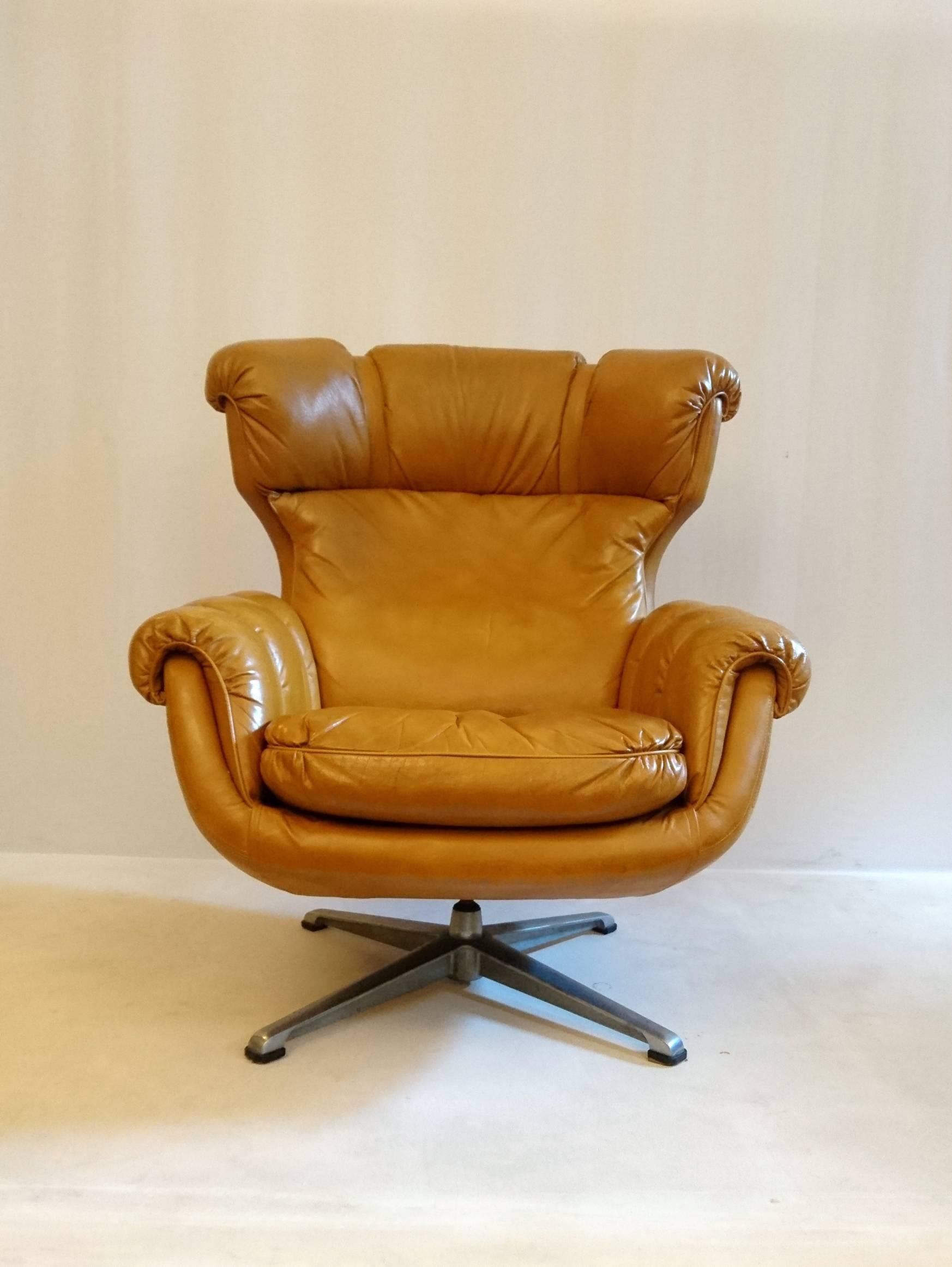 Super comfy and cool retro looking armchair from Italy in leather and with great shape. Detailing in form of belts with brass buckles.