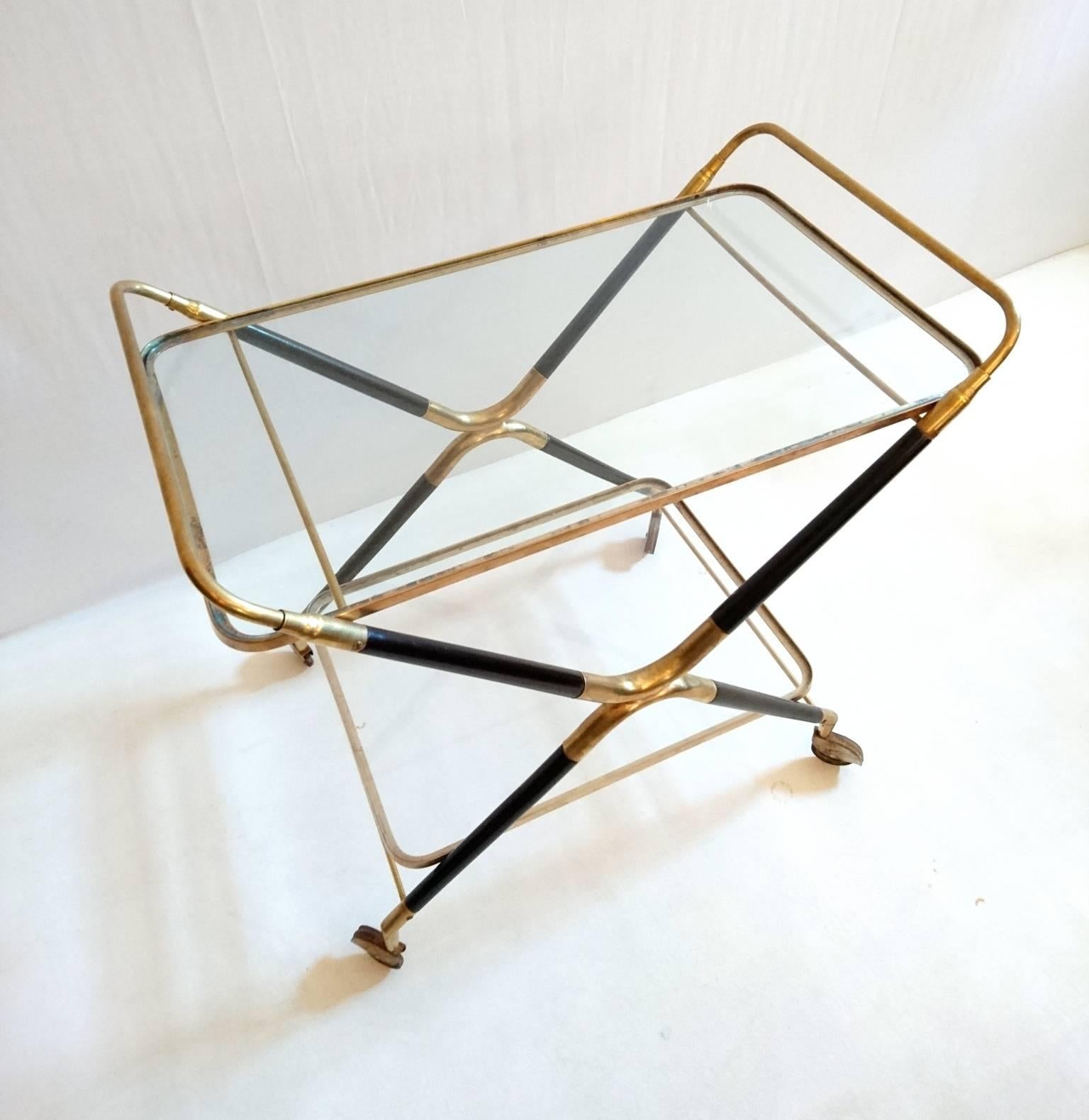 The frame is made of solid brass and mahogany with two glass shelves. Original wheels. Restored and in excellent condition.