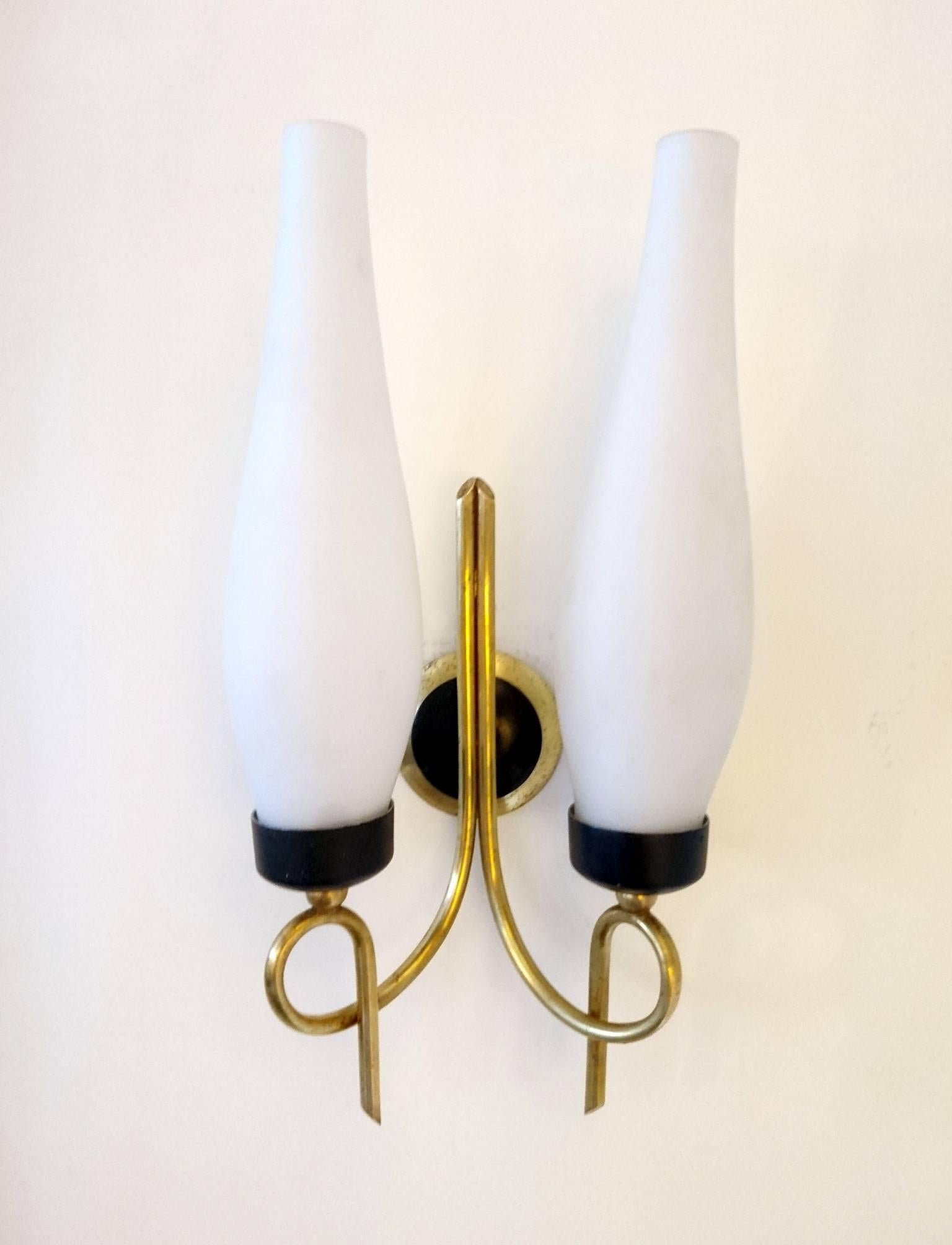Two sconces with double lights in brass and black metal with white opaque glass shades.