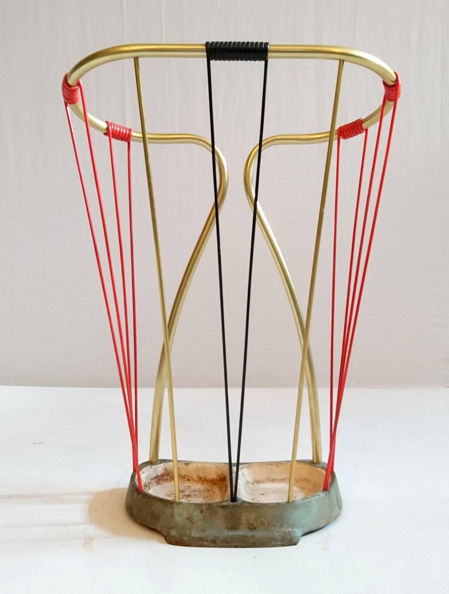 An all original umbrella stand with cast iron base and brass with plastic cord in black and red. All in nice condition. The plastic is not brittle or broken. The paint of the base is a bit rusty and can be re-painted upon request.