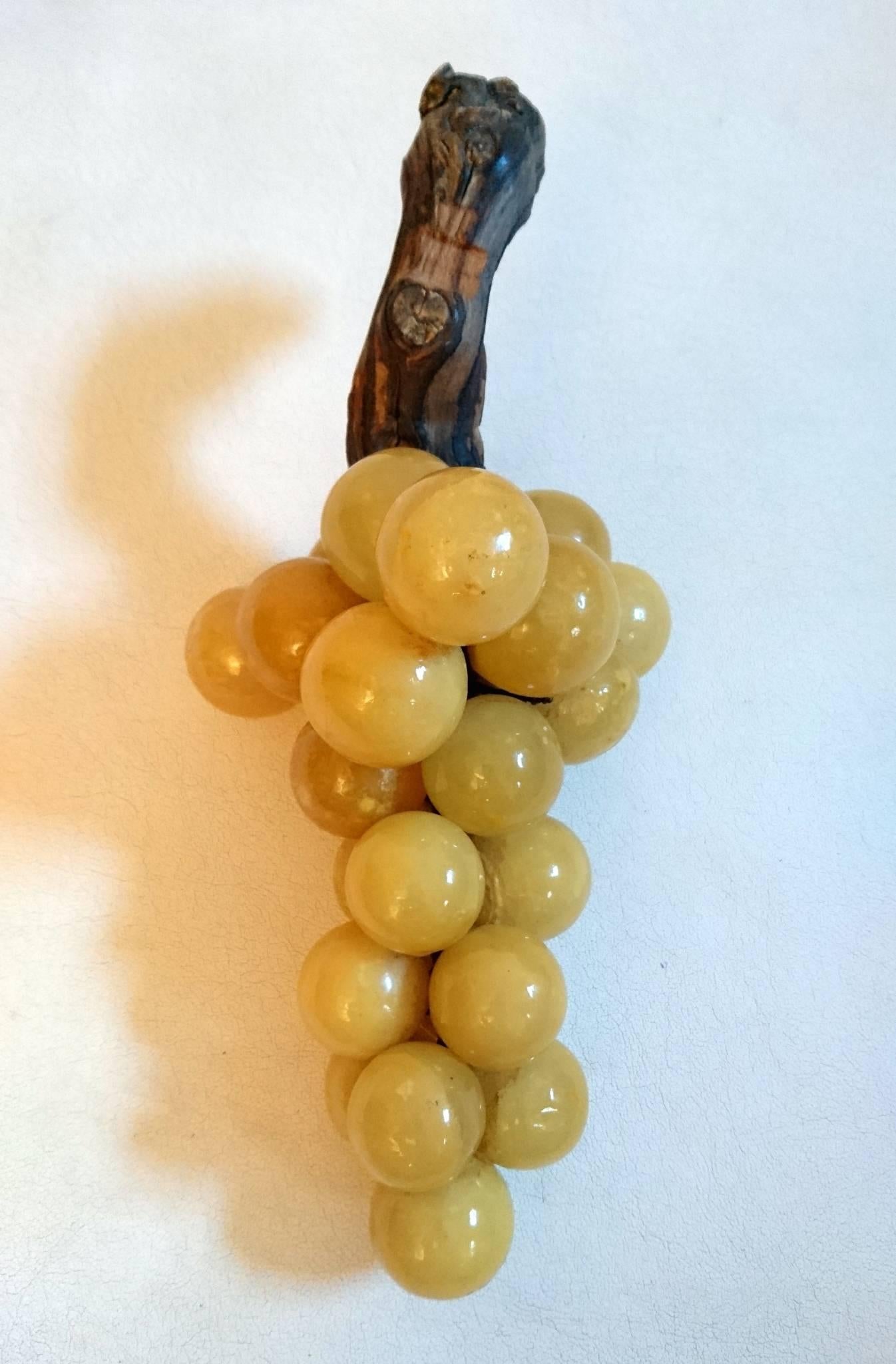 A cluster of alabaster grapes on a piece of authentic vine wood. The grapes have a yellow color tone, giving them a realistic appearance.