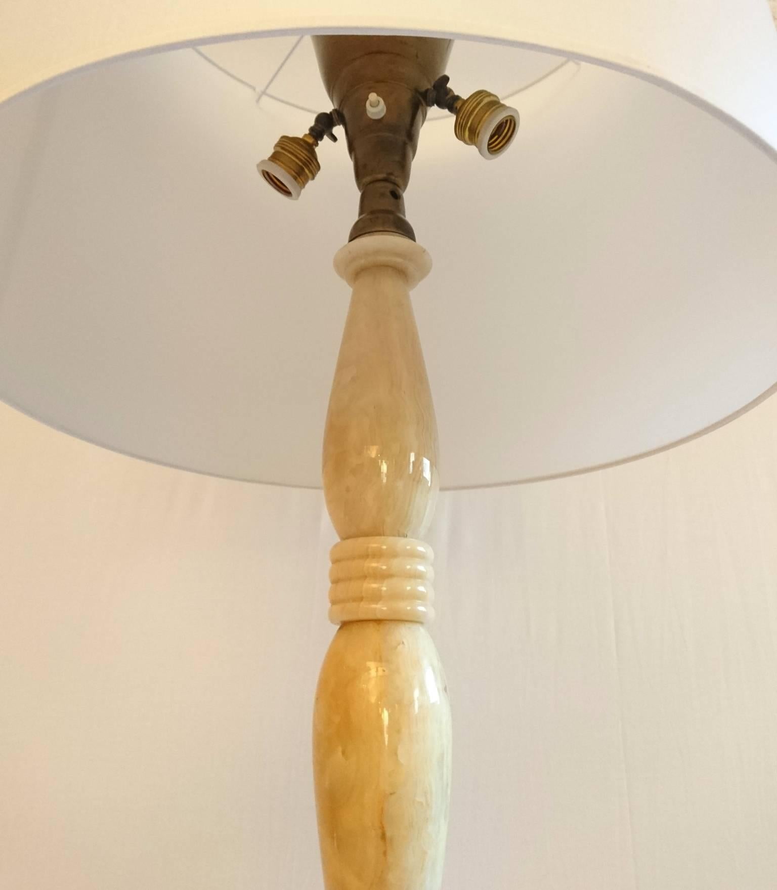 Unusual floor lamp made from beige/ivory colors lathed onyx of superb quality. Features three lamps where one functions as an uplight. In great condition without chipping or broken pieces. Comes with a new lampshade in white or black if preferred.