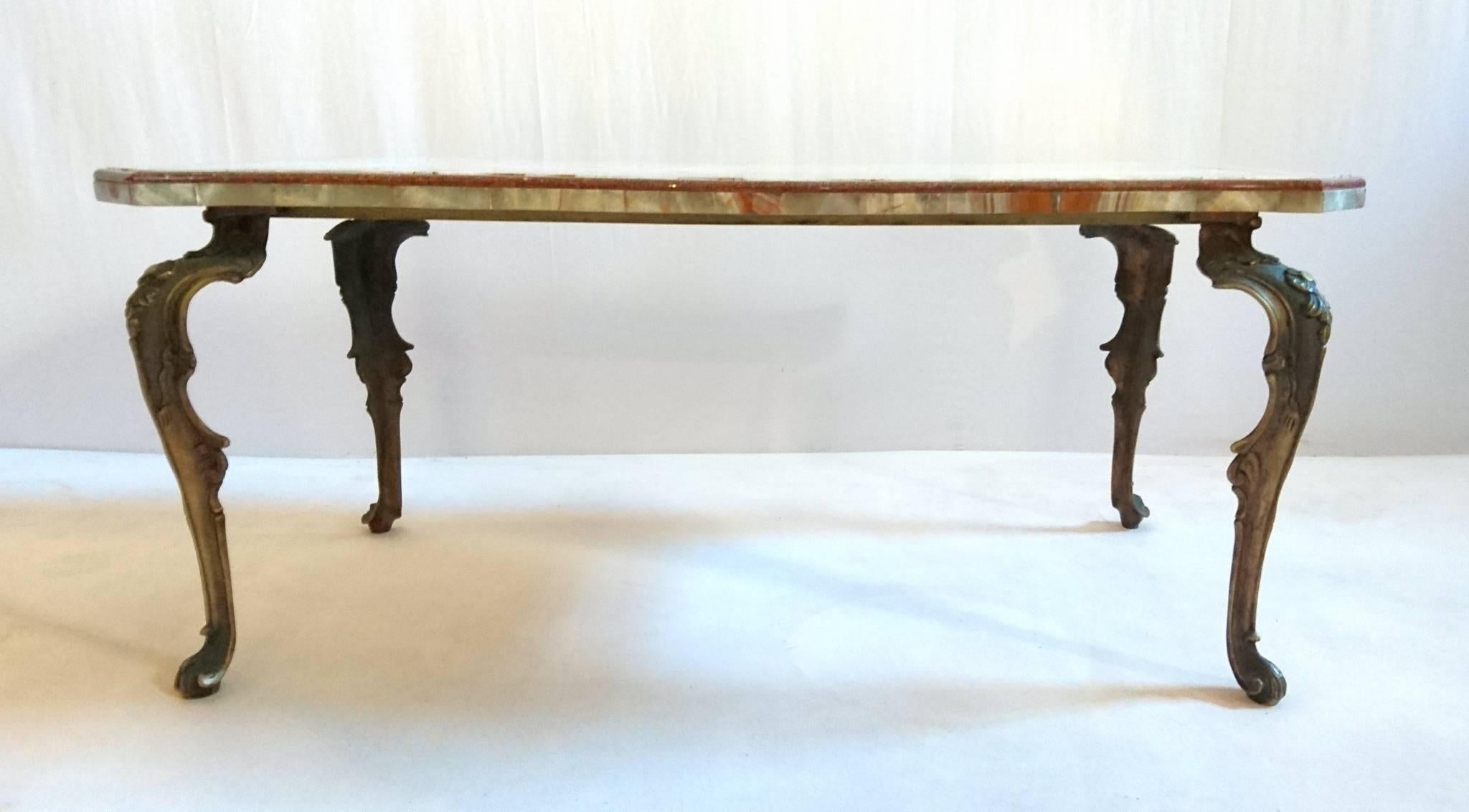 A super high quality 1950s coffee or cocktail table in Rococo style. The tabletop is made in onyx with inlaid red porphyry and the base is made from cast bronze.
