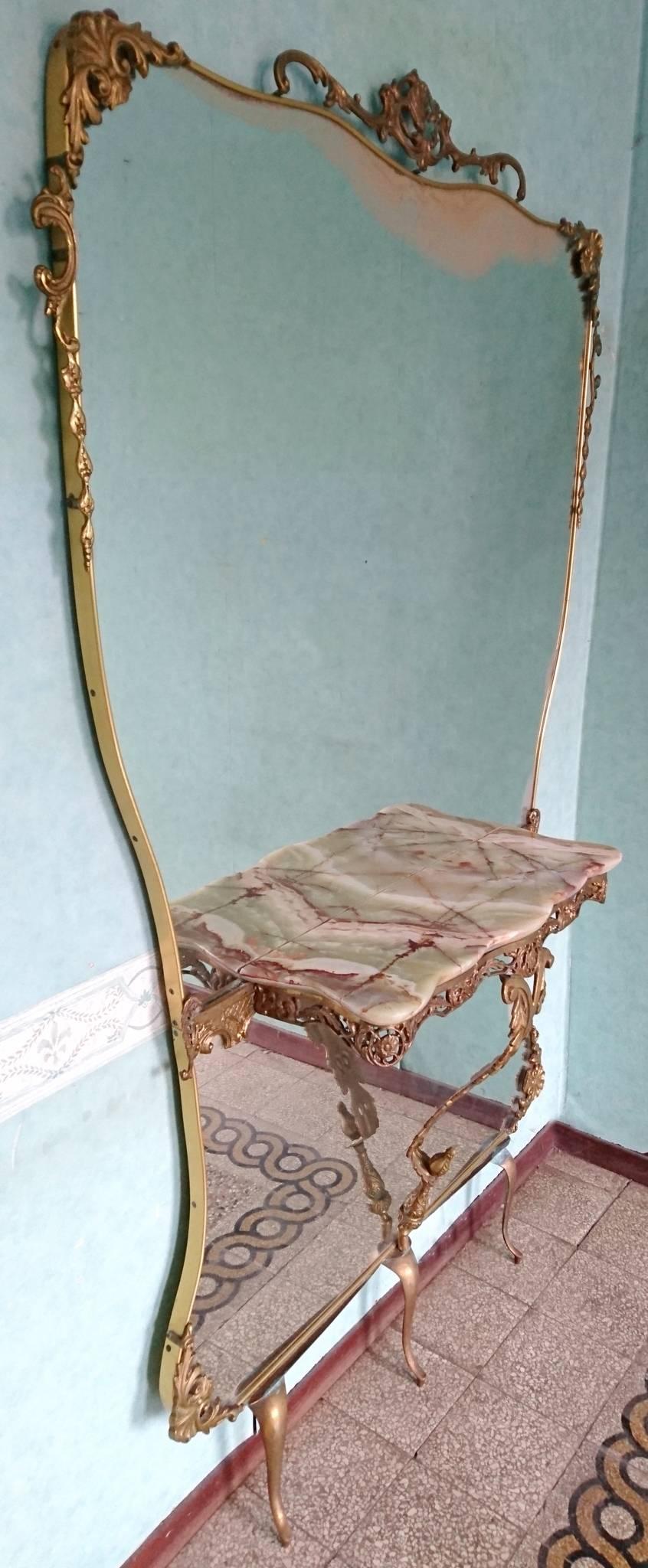 Console mirror made for the hallway or entrance. The mirror and details are in brass and the console is made of onyx in a Rococo Revival style, popular in Italy during the 1950s.