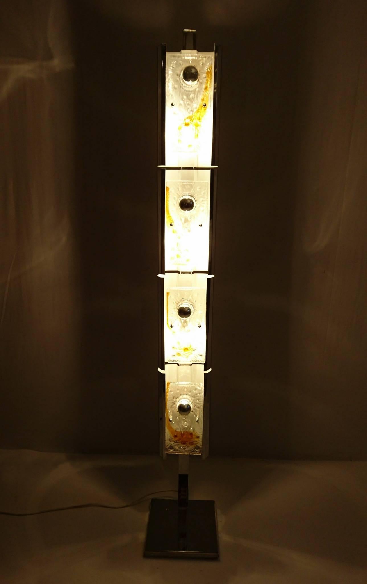 Floor lamp on a heavy chrome base with a total of eight lightbulbs. Four light bulbs sit behind the glass panels and four in front. In the picture the visible lamps are silver capped which gives a perfect ambience and reflecion of the glass panels.