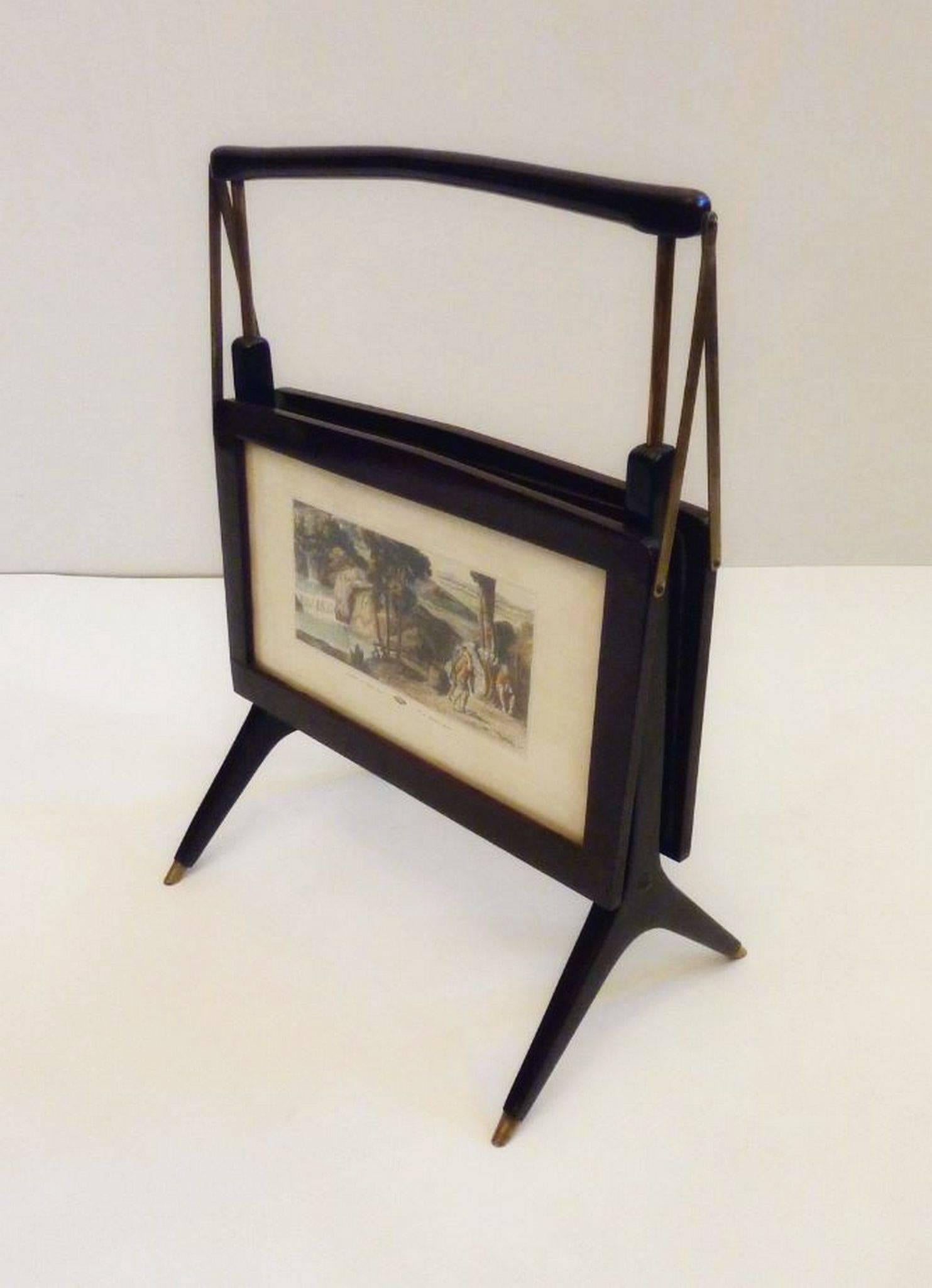 1950s foldable magazine rack in stained beech wood and brass detailing. Features pastoral landscape scenes on each side posted behind glass.