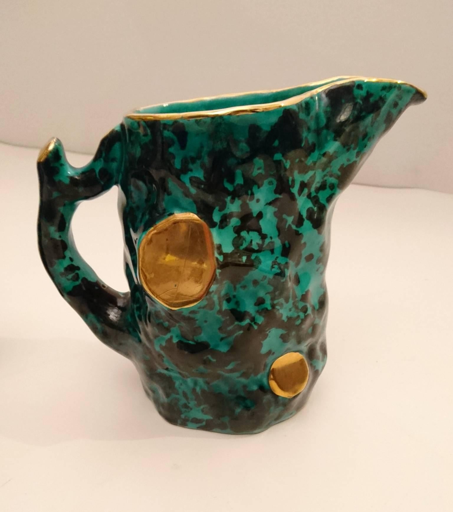 Raro set di sei tazze e una brocca in un particolare colore verde mare intenso e nero con puntini dorati delle ceramiche Pucci provenienti dalla città di Umbertide, in provincia di Perugia. La fabbrica si concentrava principalmente su prodotti