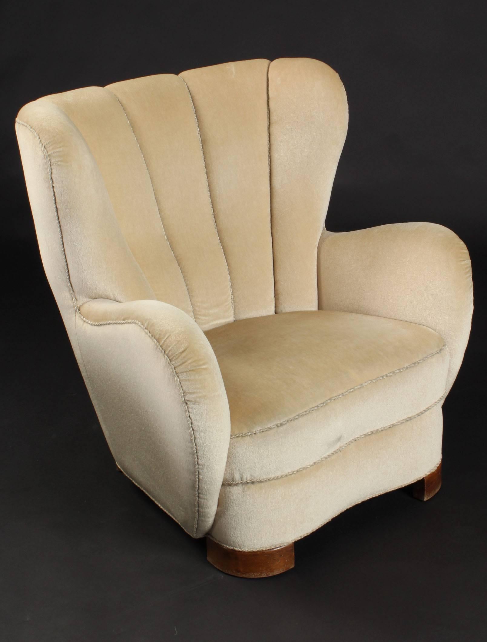 Comfortable curved wingback armchair produced in Denmark in the 1940s. It is in its original condition with ivory mohair fabric. The block legs are made of beech wood. See also the matching sofa in the same form and fabric.