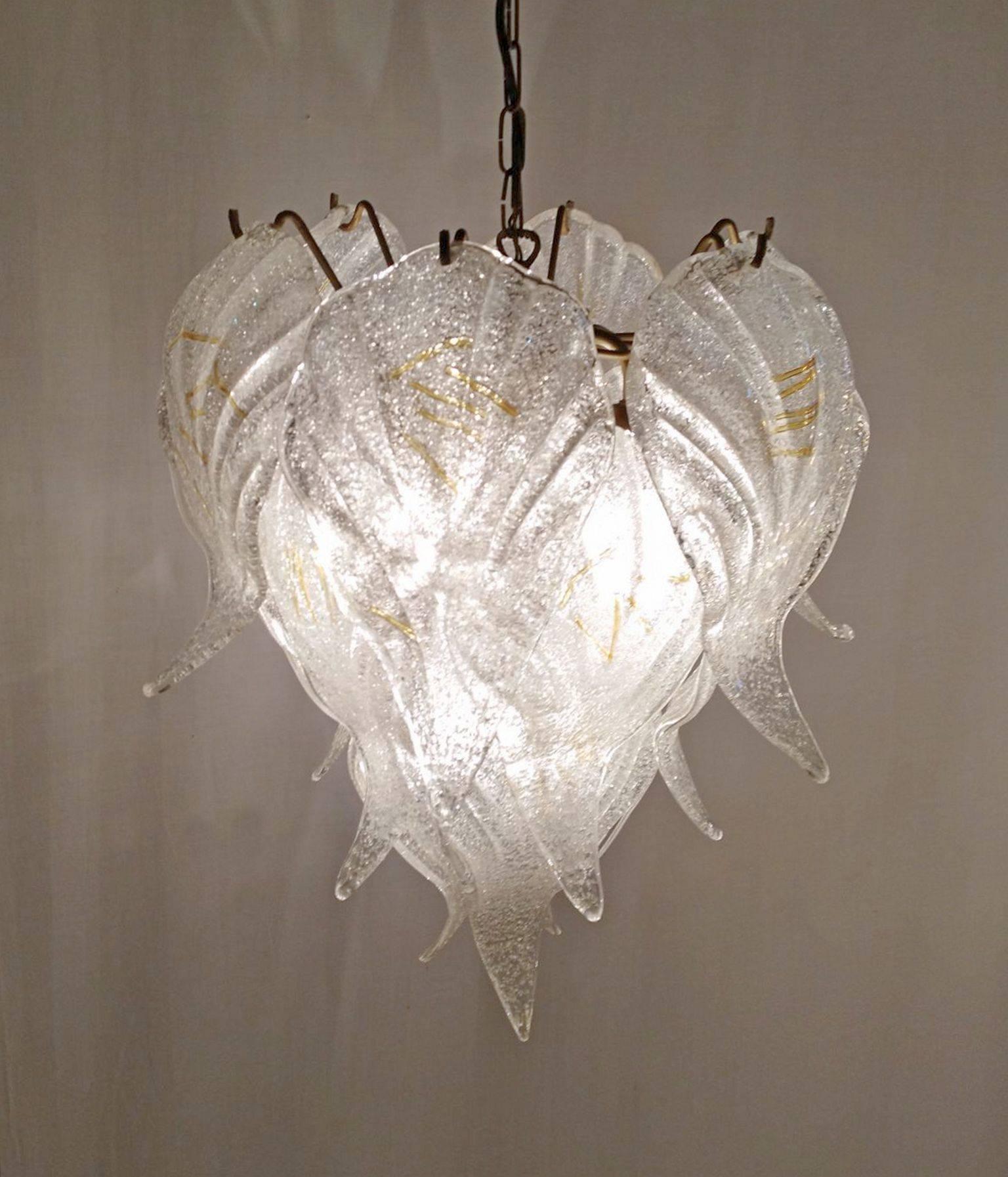 A 1960s swanky chandelier made in Murano, Italy by Mazzega. Features 15 large frosted textured glass pieces shaped like leafs hanging from a gold colored structure. The lamp without chain measures 60 cm. And complete it is 110cm. Can be delivered