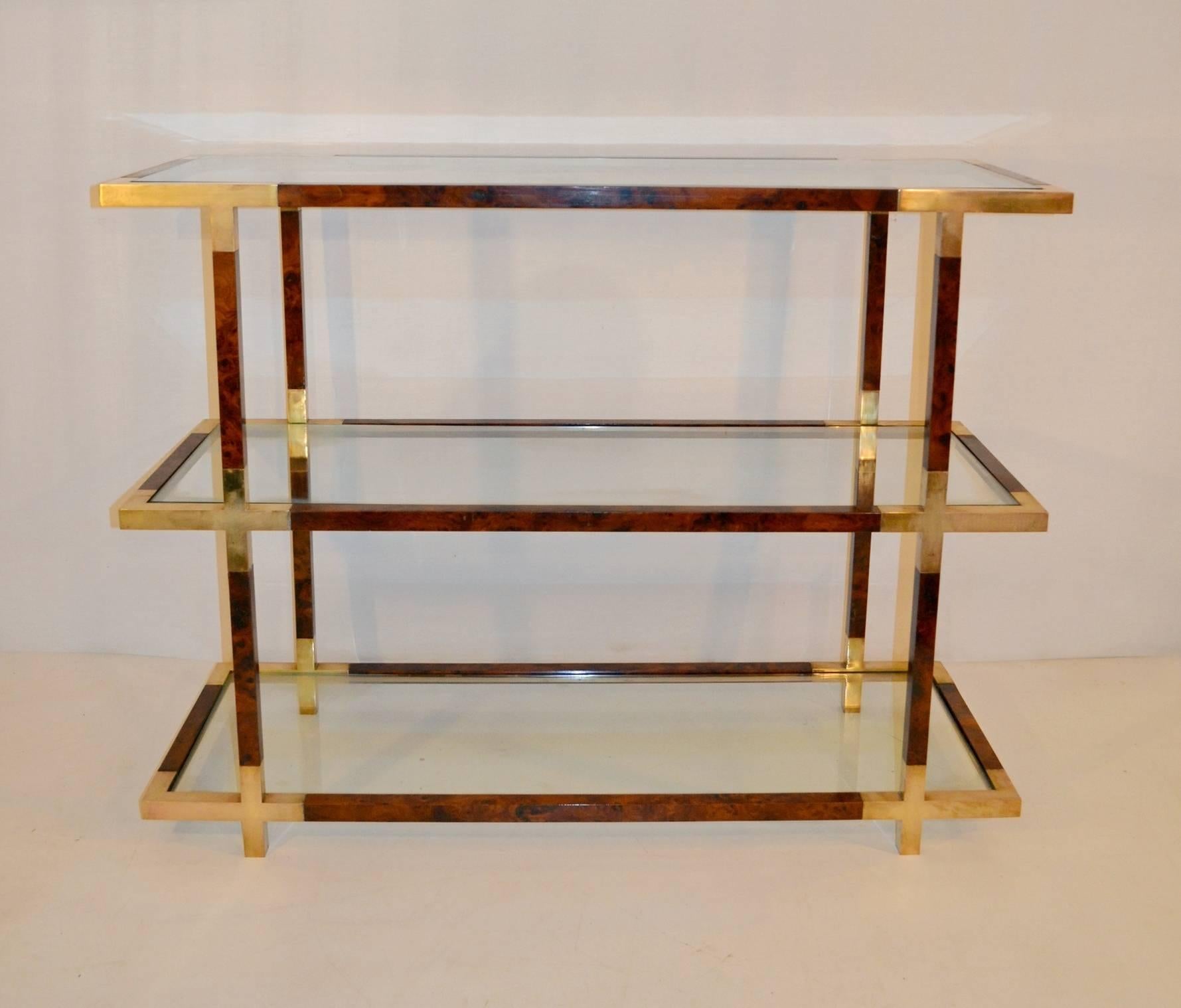 A three tiered etageré with clear glass shelves and a structure in burl wood and brass details. In excellent condition and quality. This piece can be freestanding in a room or in a window as it doesn´t have a backside.