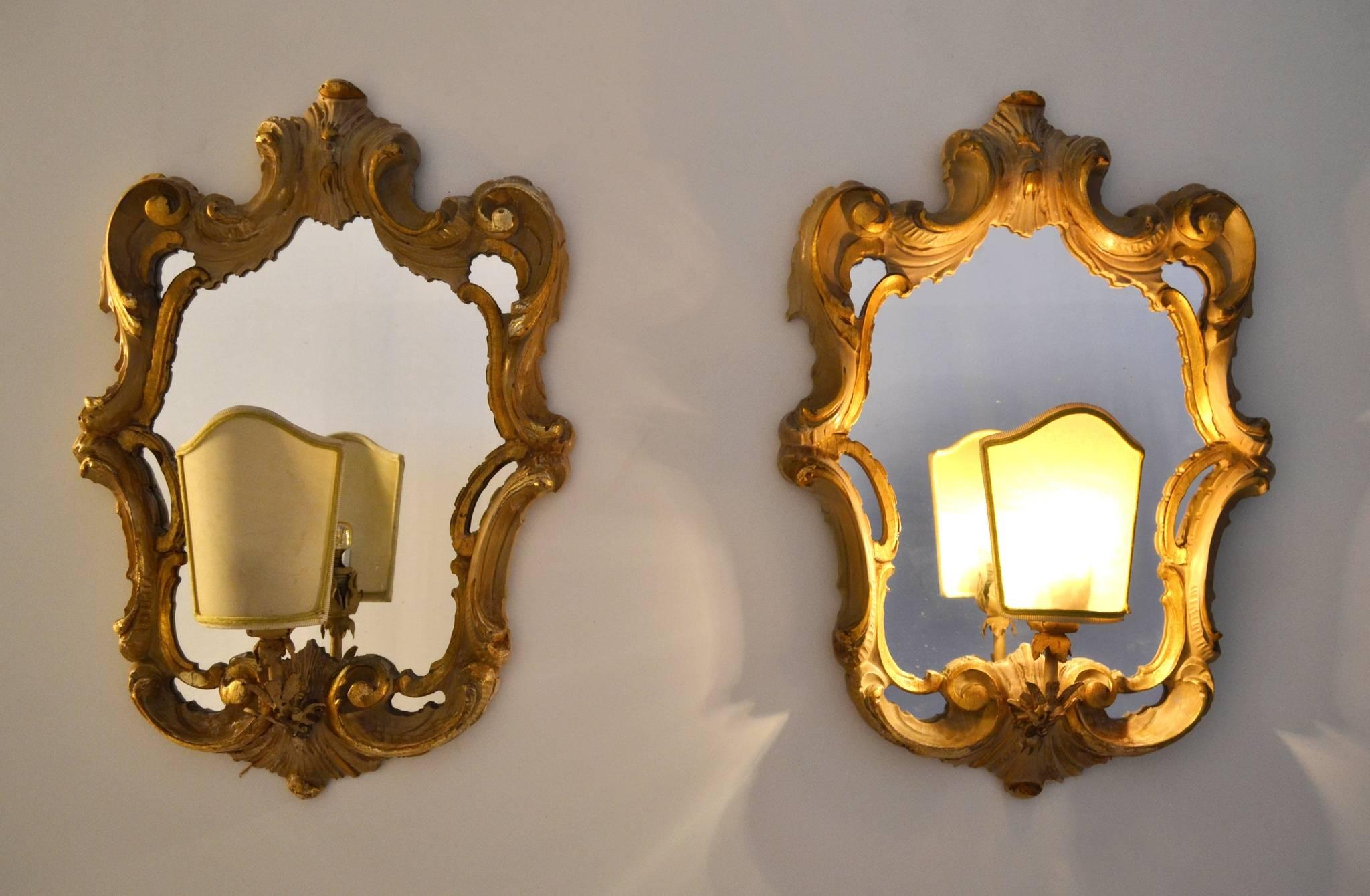A pair of ivory and gold colored electrified hand-carved wall sconces in Rococo style produced circa 1940 in Italy.