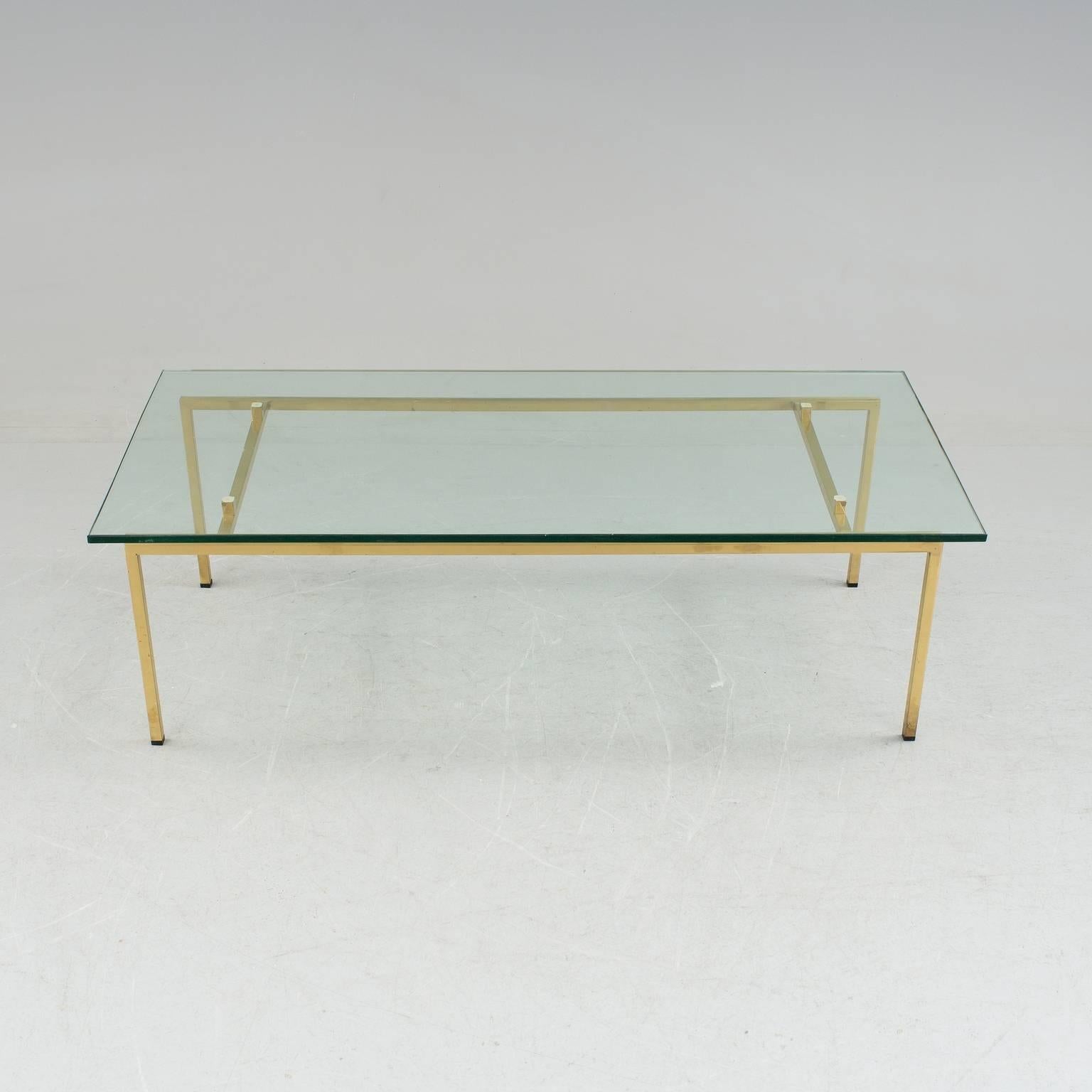 Coffee table with a solid brass base and a heavy clear glass top with a simple yet elegant design.