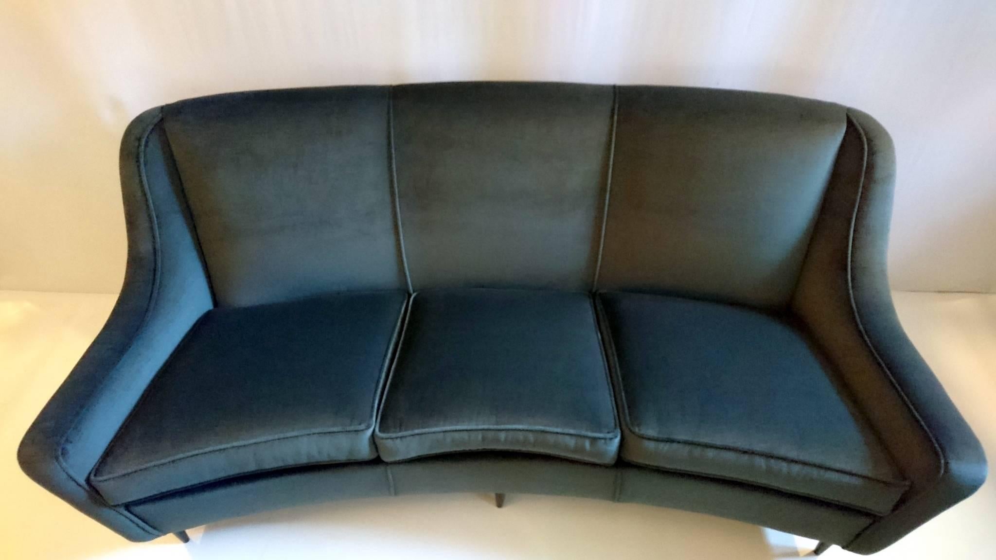 This sofa has recently been professionally completely reupholstered in a soft grey velvet fabric. Seats three people comfortably. Has blackened wooden legs.