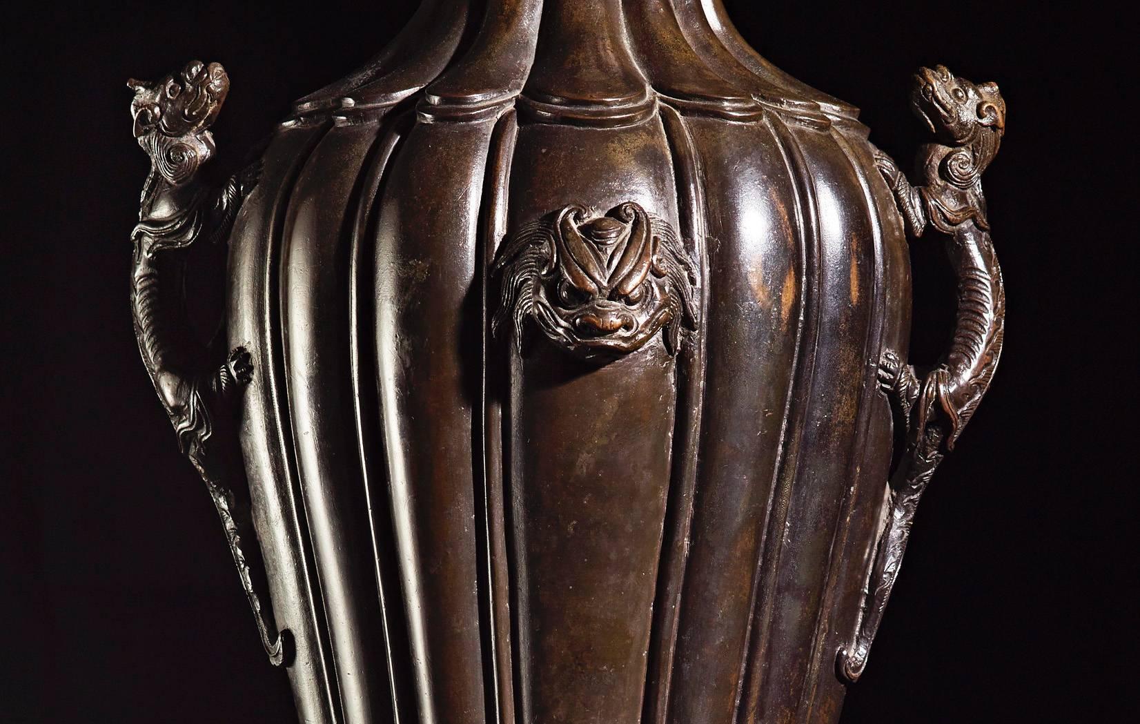 Important vase.
Bronze with wood stand,
china, 17th century.
High: 55 cm. 

Baluster vase with lobed cut is which has a pair of chilong dragon handles to the sides. They are separated by two protruding mythical beast heads which dominate the upper