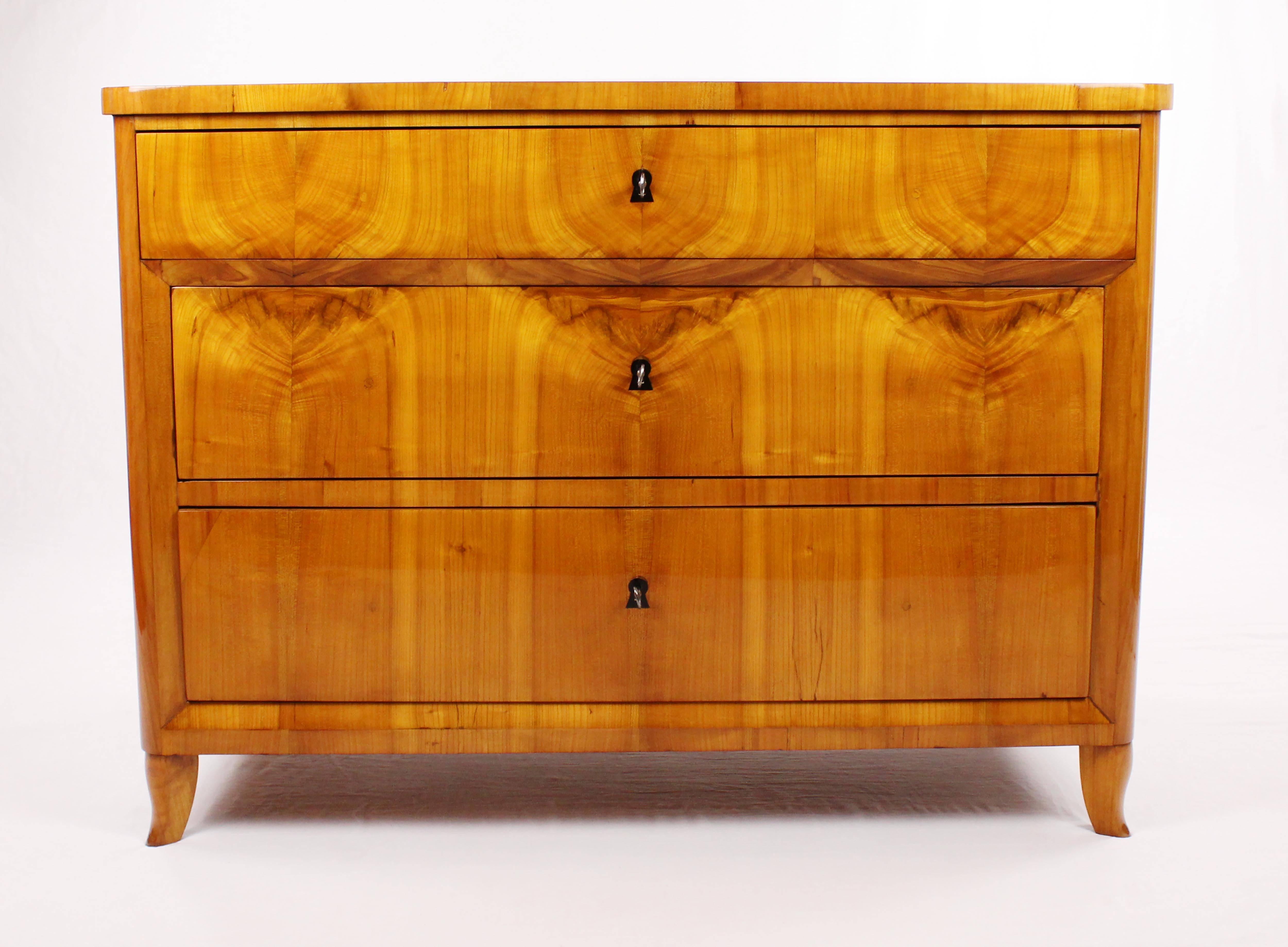 • Biedermeier period chest of drawers, circa 1820-1830
• Cherry tree veneer
• 3 drawers
• Unique reflected veneer
• Ebonized key signs
• Rounded corners
• Restored state
• French shellac hand polish
• Height 86.5 cm, width 117 cm, depth 57