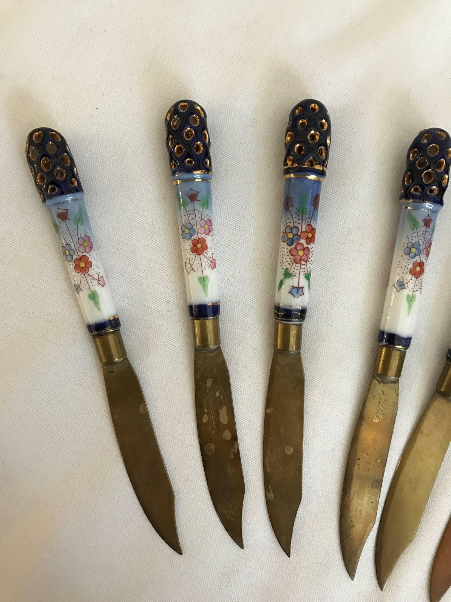 Set of 12 made in Austria cheese or fruit knives brass with porcelain handles. Beautiful design. The porcelain is a beautiful white with royal blue and gold and hand-painted flowers in coral, blush and blue. Very pretty statement pieces. Would make