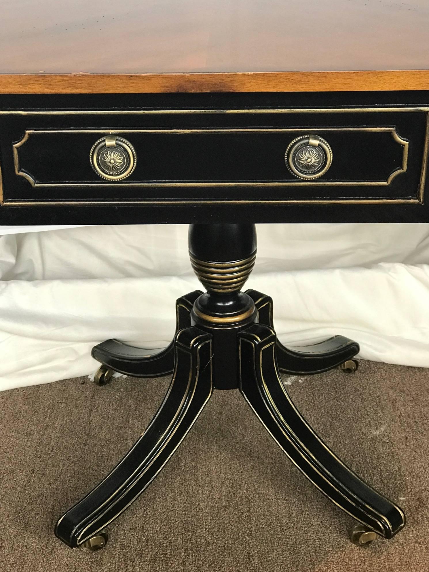 On Sale Now!  Neoclassical style ebony and gilt rent collector's table with gilt gold accents and brass pulls. Beautifully set on a tripod base that sits on wheels. The top is octagon shaped and follows down to false drawers on the front and back