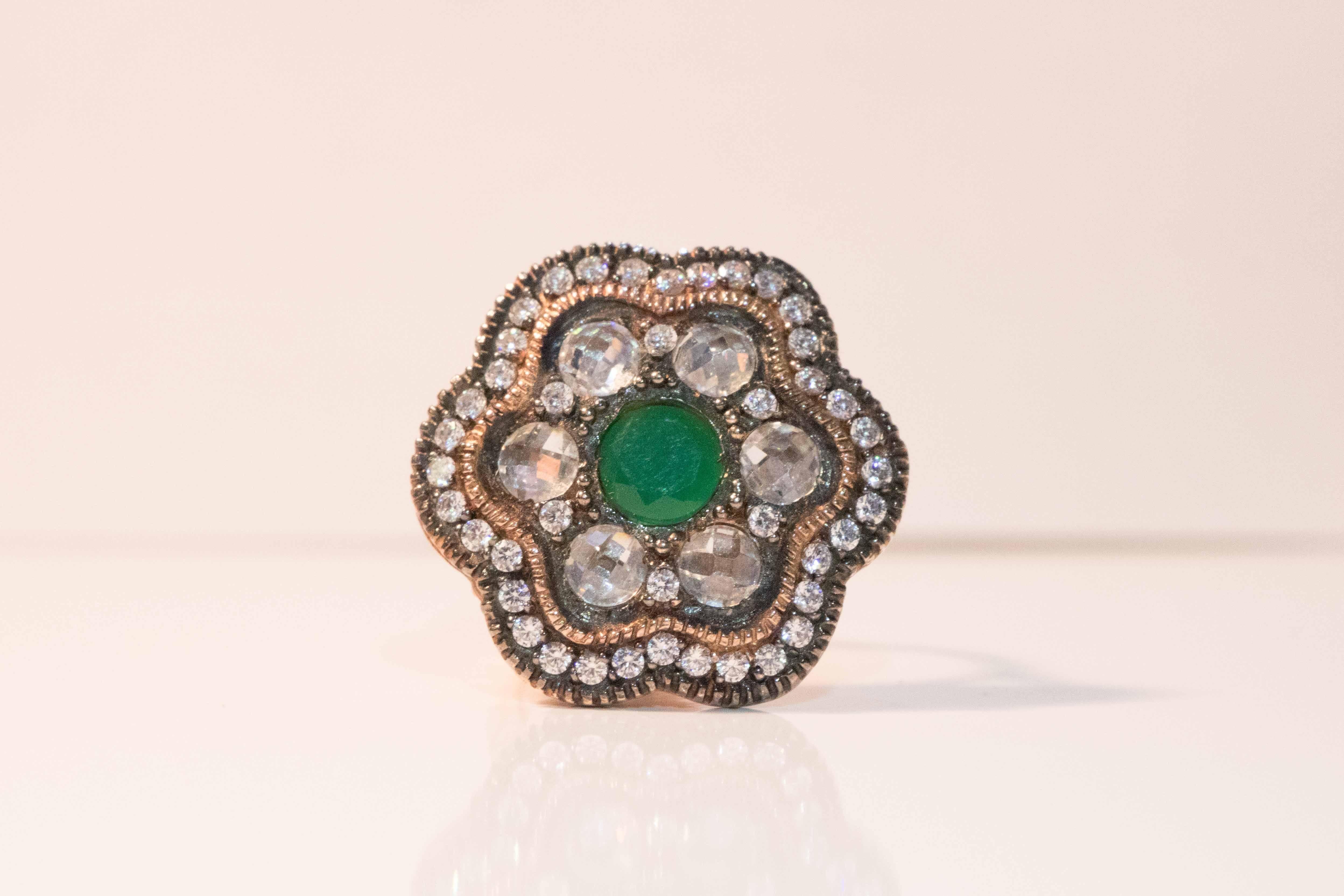 Stunning vintage Swavorski Emerald, Zirconia and crystal .925 rose plated ring. Add a vintage touch to any outfit. Lovely emerald center stone measuring .75 surrounded by .25 each Cubic Zirconia making a total of 6. Many stones within stones –