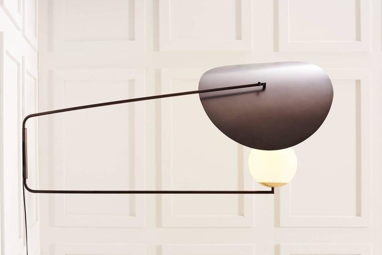 Designed to mimic the classic image of a beautiful woman shading her face with a wide brimmed hat. This wall light has swiveling arms and a rotating reflector, allowing one to direct the light and shade the globe as desired.

This piece can be hard