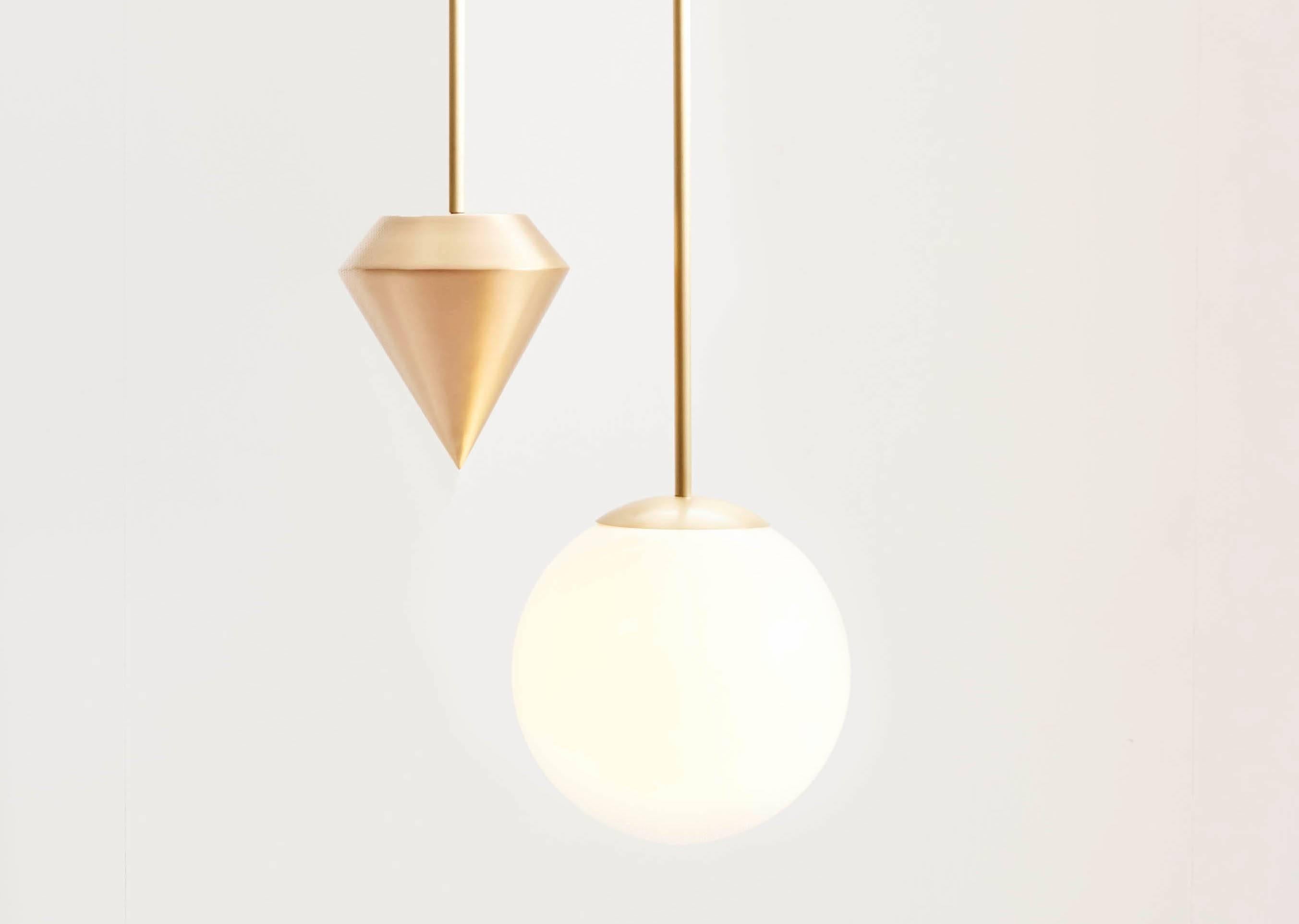 A white glass orb hangs side-by-side with our signature plumb weight, counter-balanced end points to a dramatic vertical arch.

Available in brushed brass and oil rubbed bronze. Ceiling stem lengths are cut to your requirements. Available in two
