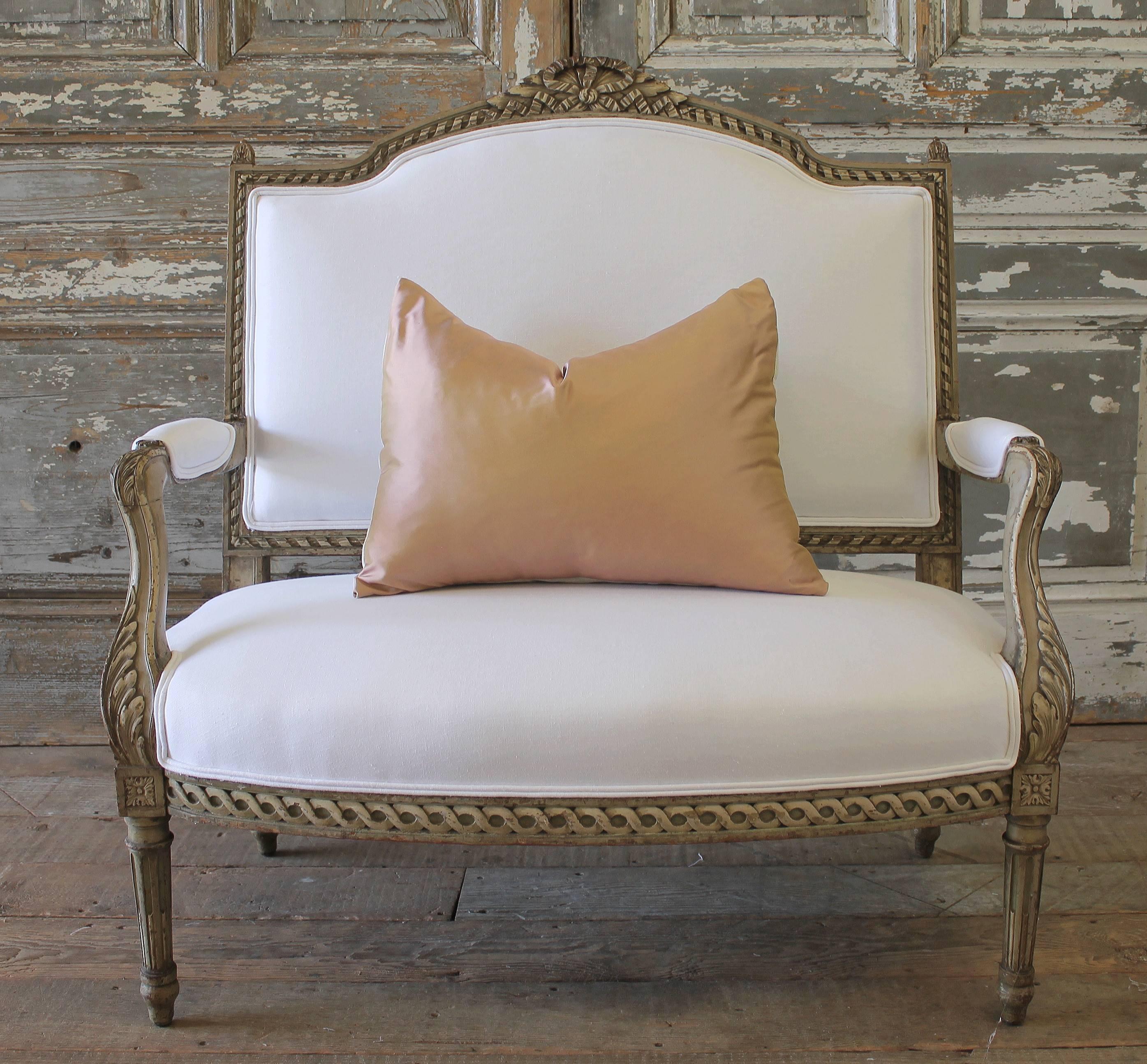 Beautiful French Country Louis XVI settee with original paint finish. The color of the frame is a soft greyish-taupe with darkened accent glaze rubbed into the carvings. The carvings are done very well, with a large ribbon and curled ribbon along