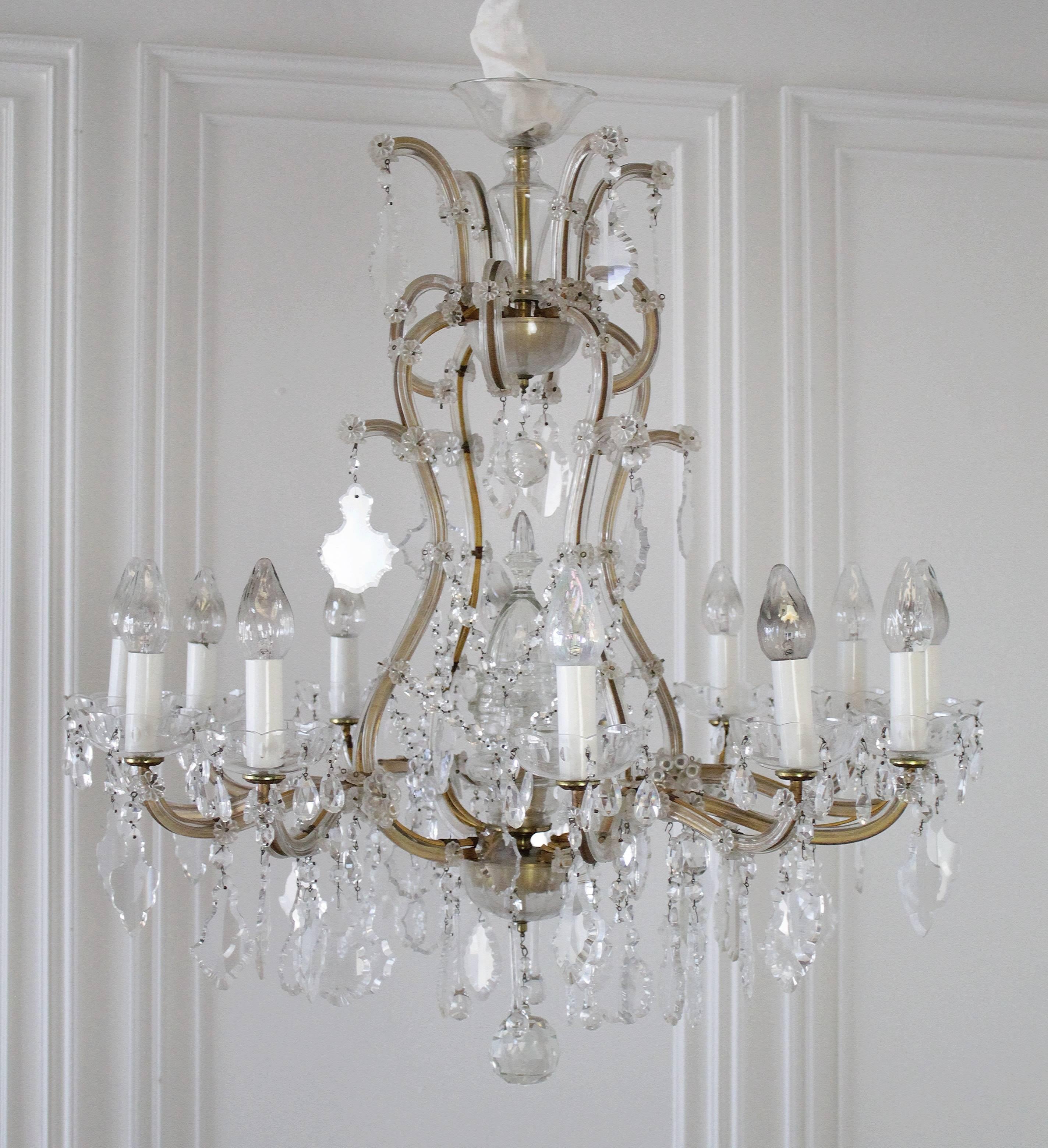 An exquisite, well-proportioned Marie Therese style chandelier. The 12 arms of lights spread over a beautiful cut-glass pans, the frame adorned with cut-glass plaques, beads and rosettes and a central pyramidal cut-glass element houses an additional