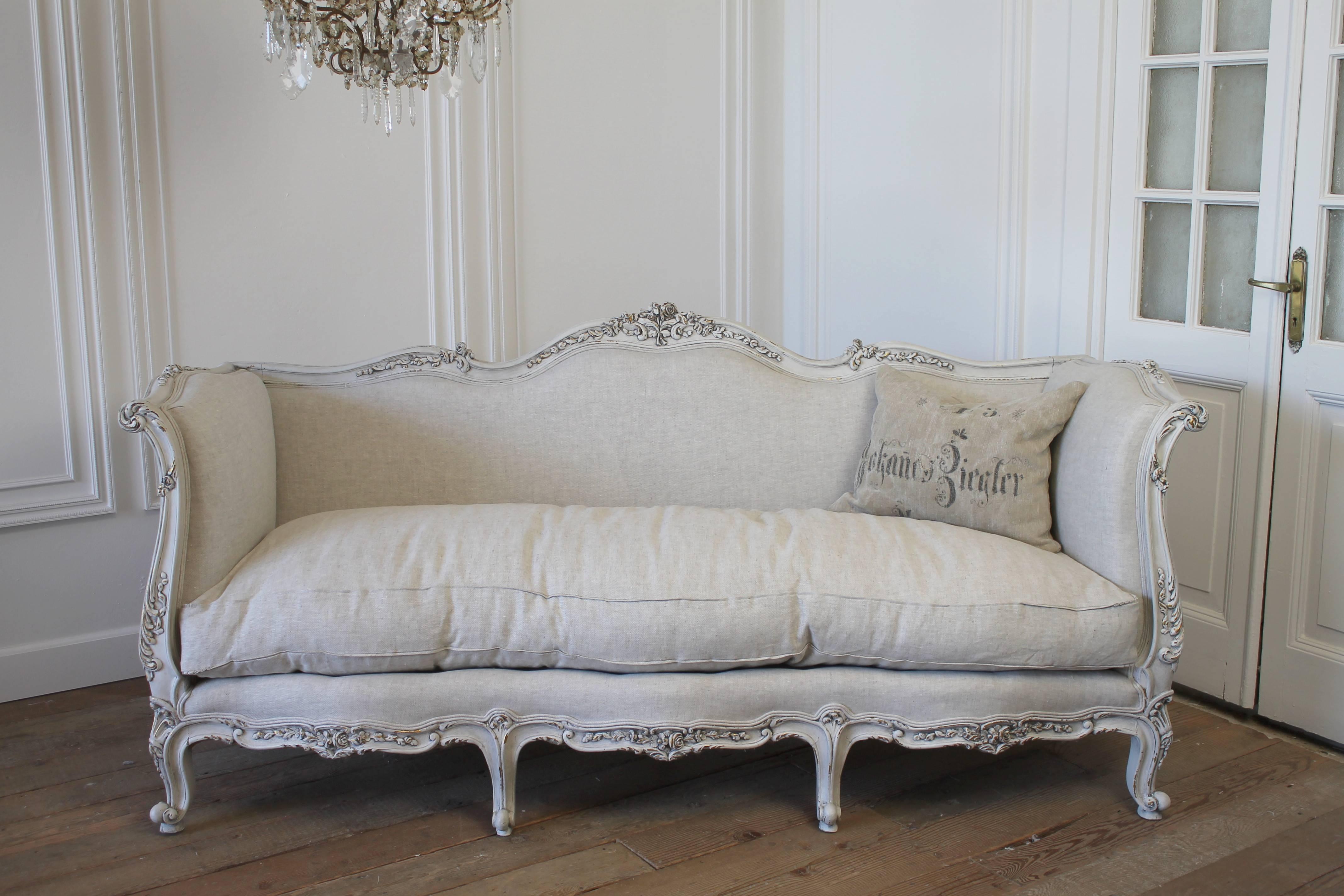The sofa has been painted in a soft oyster white color with some of the gilt peeking through. The finish has been given an aged waxed to give the appearance of an original patina. The sofa has been reupholstered in a 15oz Belgian linen, the color is