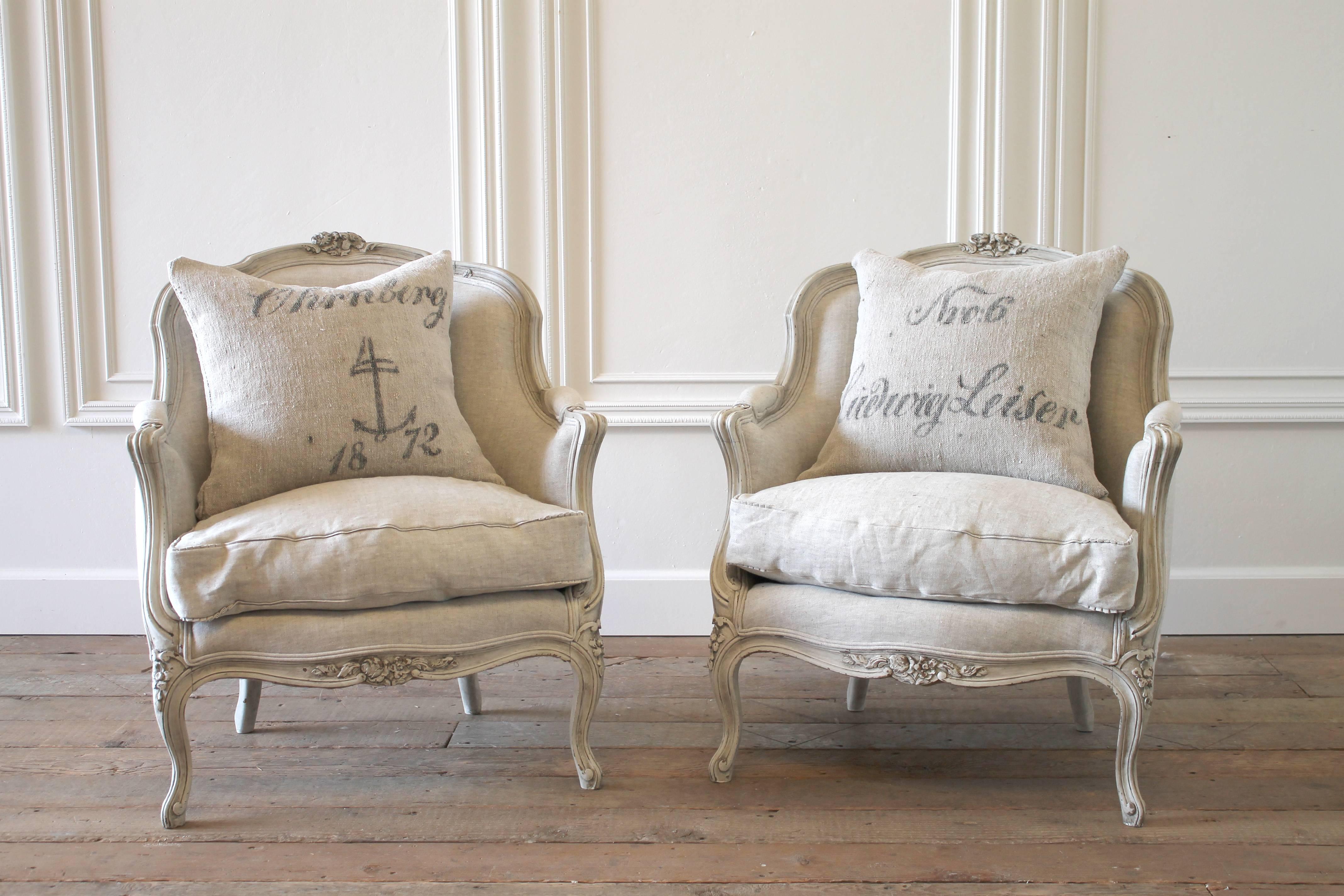 Fabulous pair of Louis XV style bergeres, painted in our signature oyster white finish, highlighted with an antique glaze to give the look of a time worn patina. Chairs are solid carved walnut, and very solid and sturdy, ready for everyday use. The